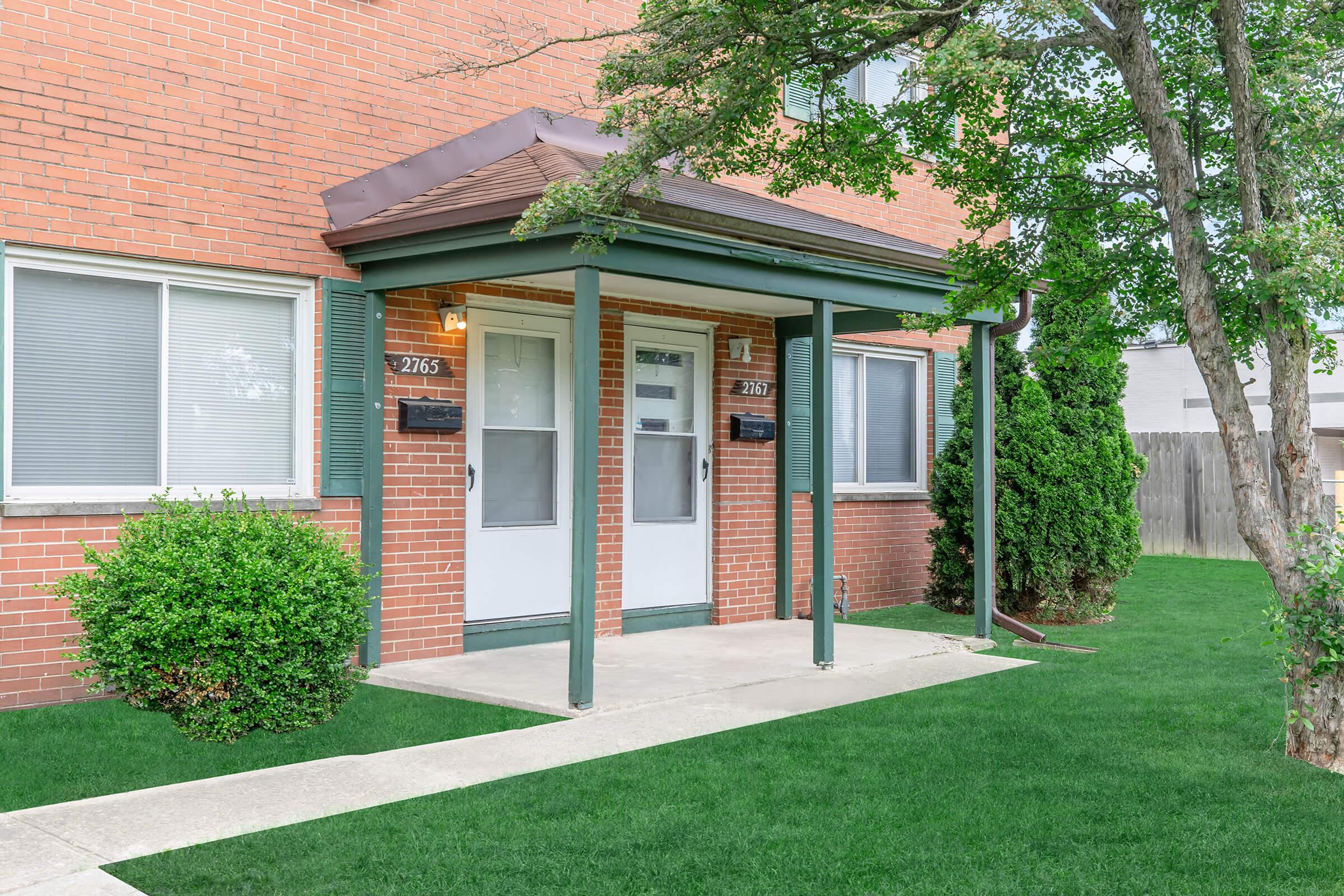 a house with a lawn in front of a brick building