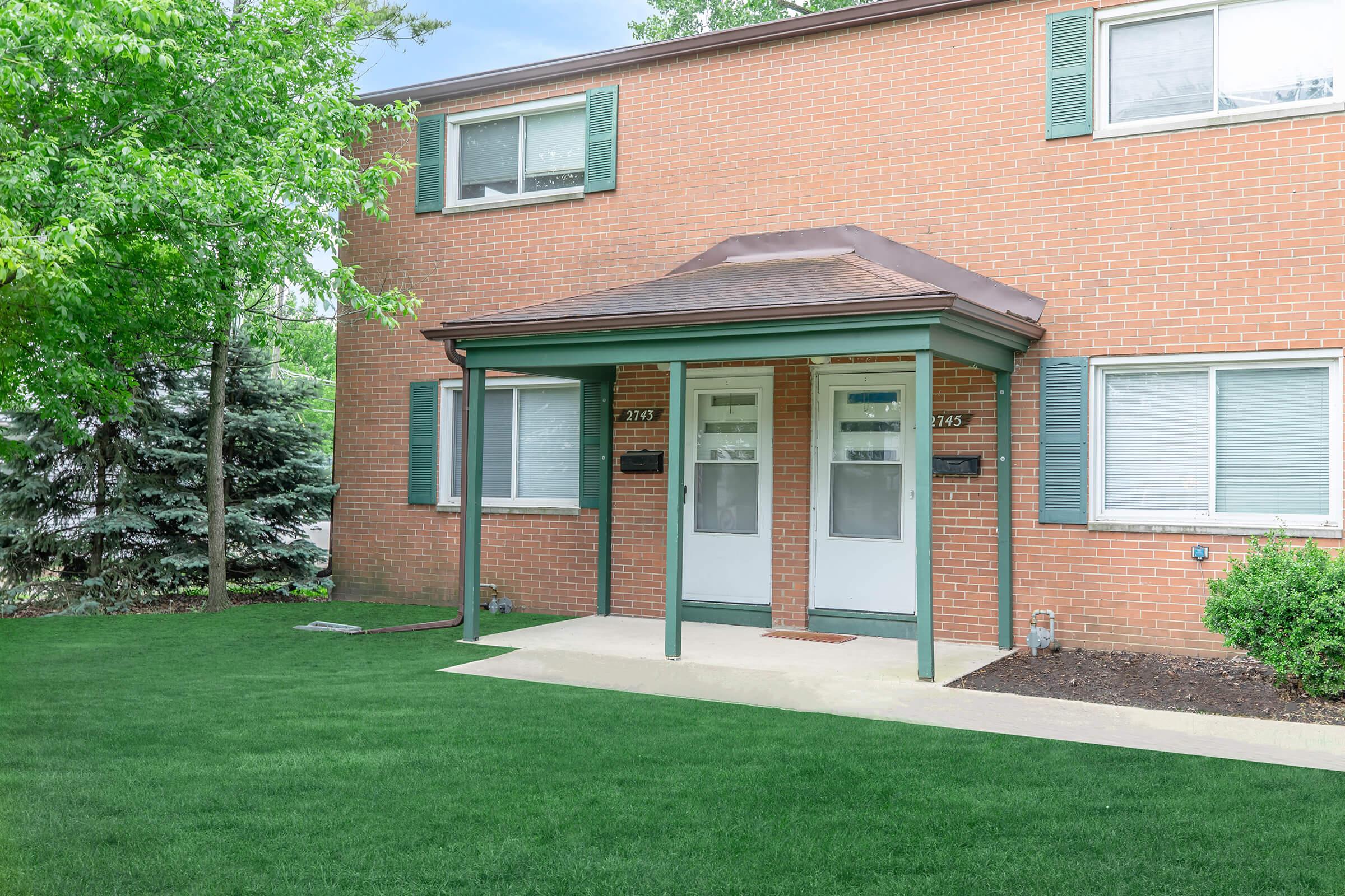 a house with a lawn in front of a brick building