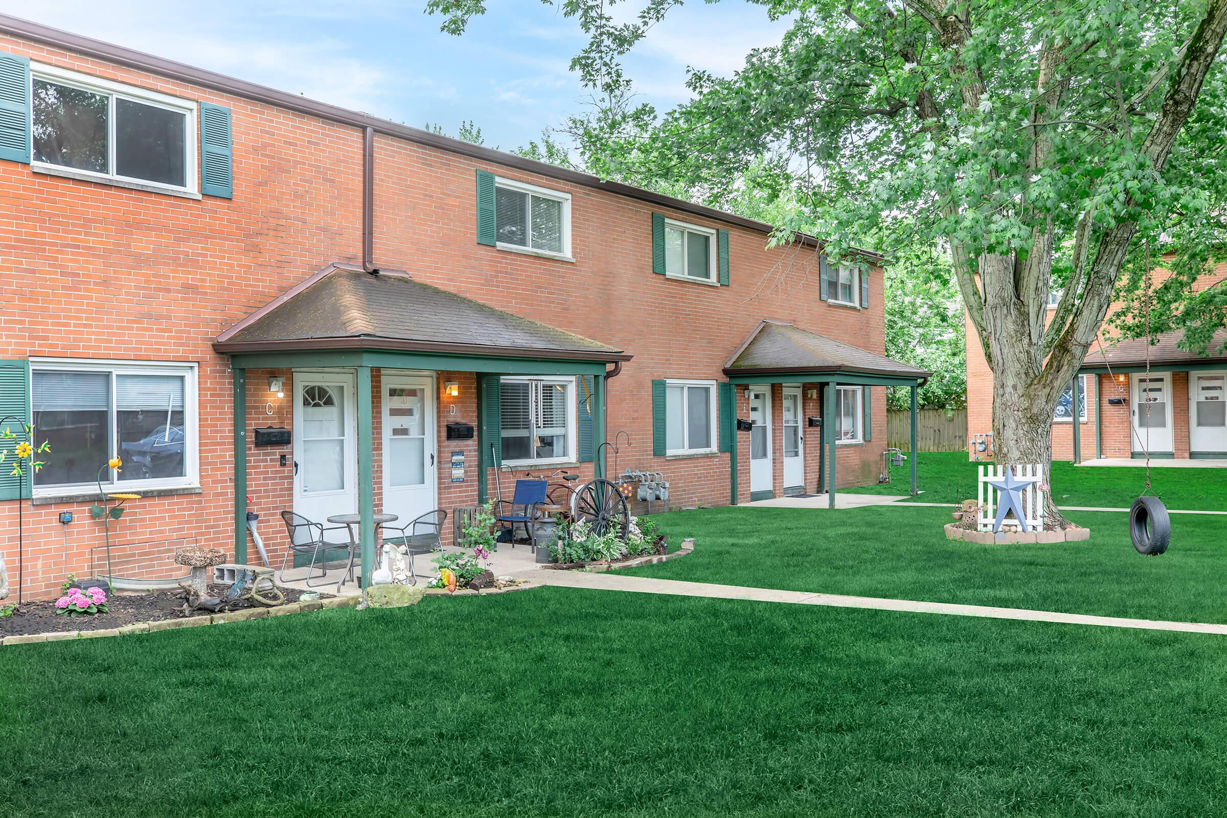 a house with a lawn in front of a brick building