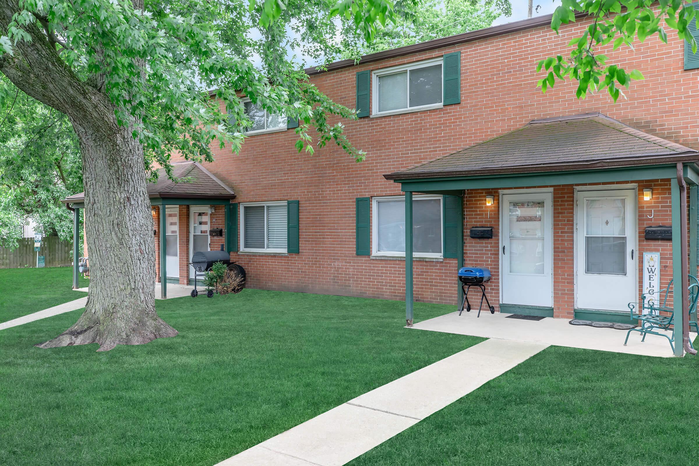 a house with a lawn in front of a brick building