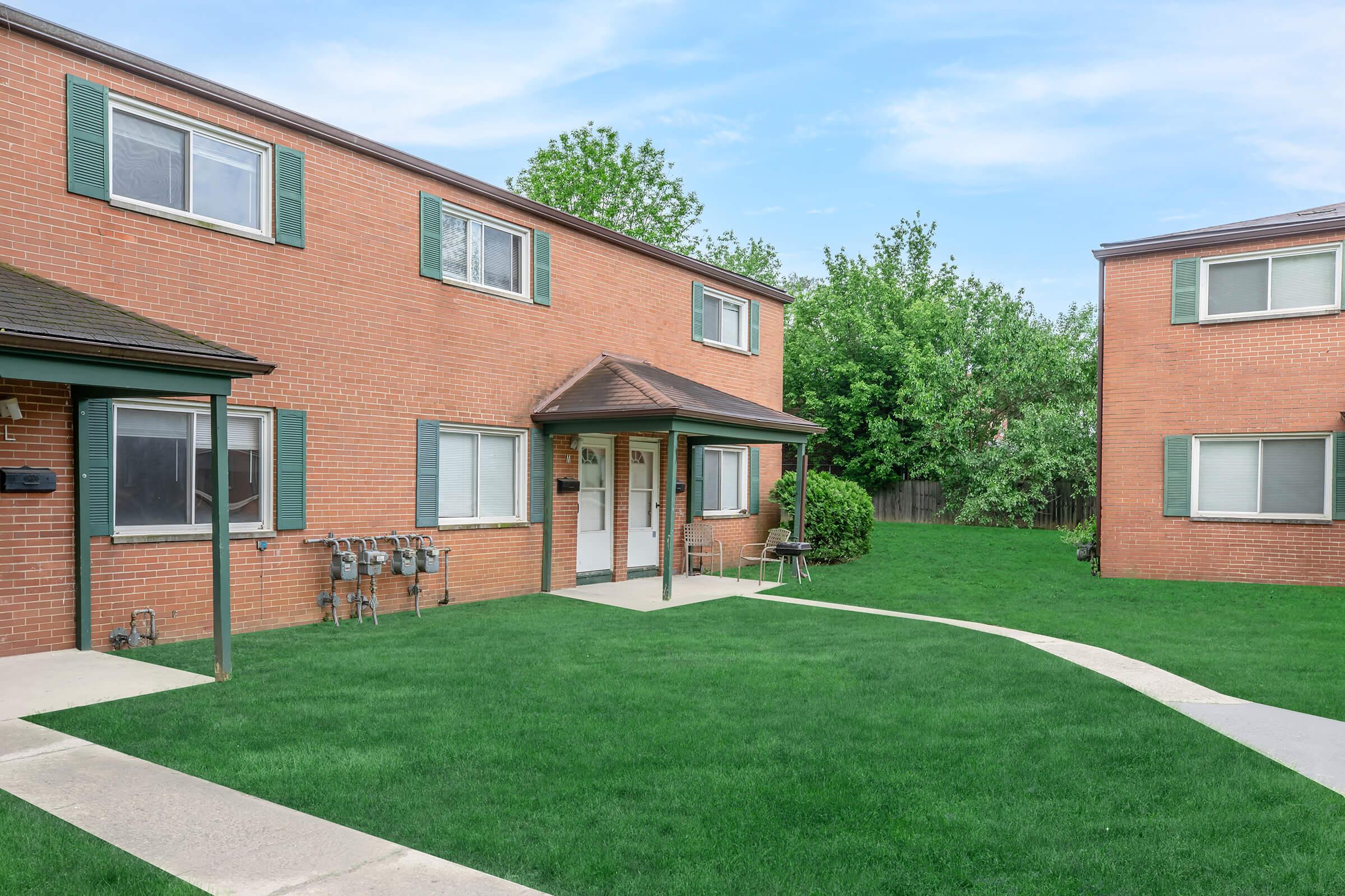 a house with a lawn in front of a brick building