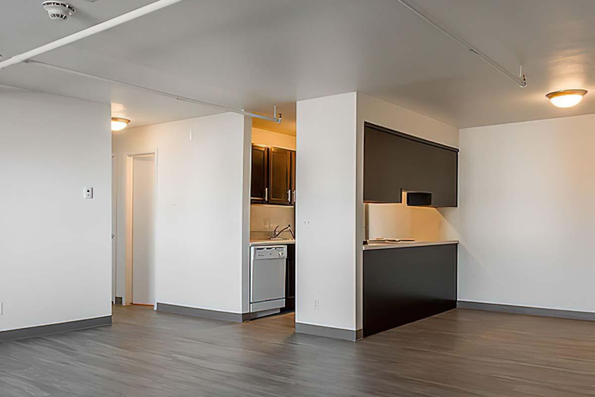 Modern kitchen in an open-concept living space featuring dark cabinetry, a white countertop, and stainless steel appliances.