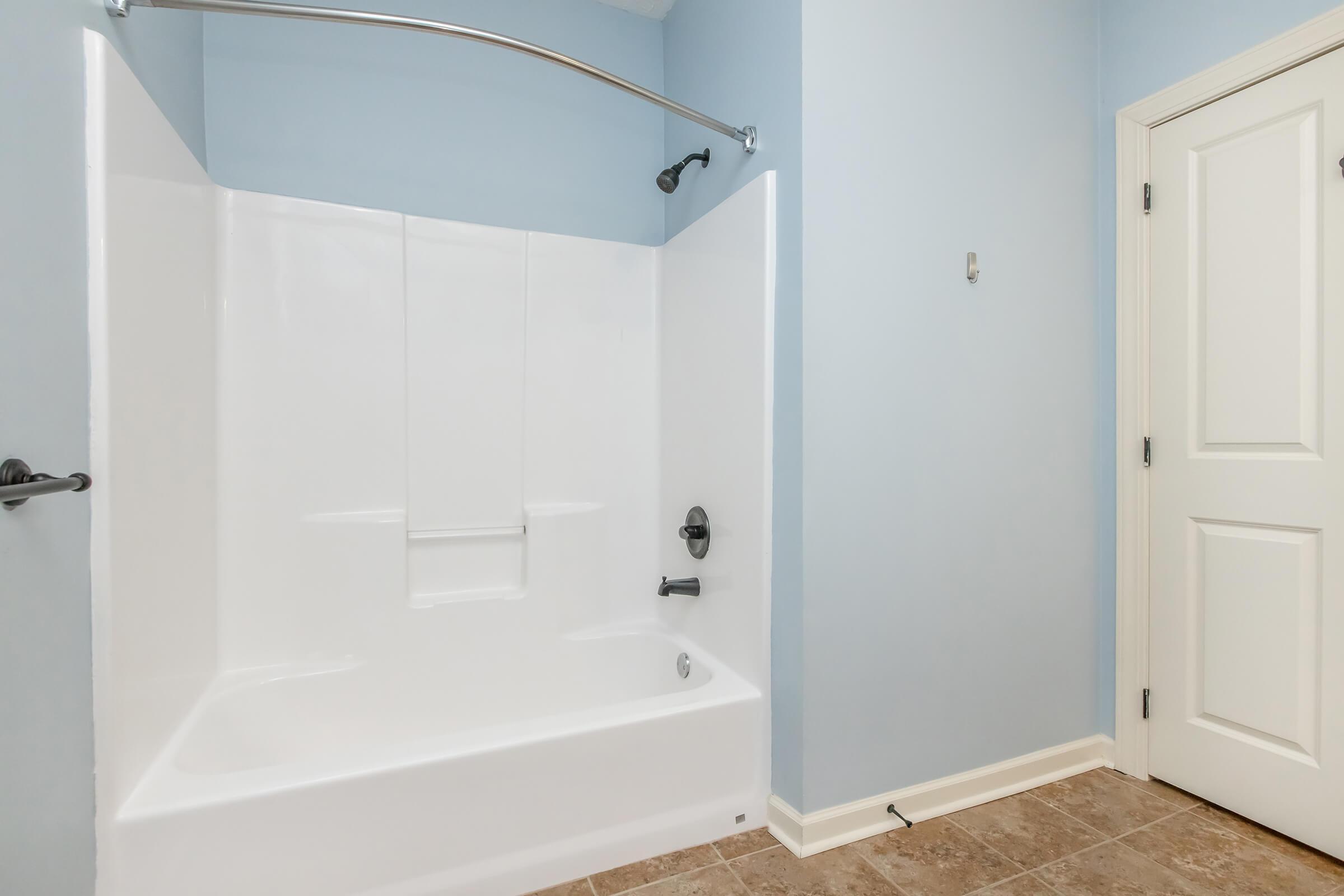 tub and shower with tile flooring