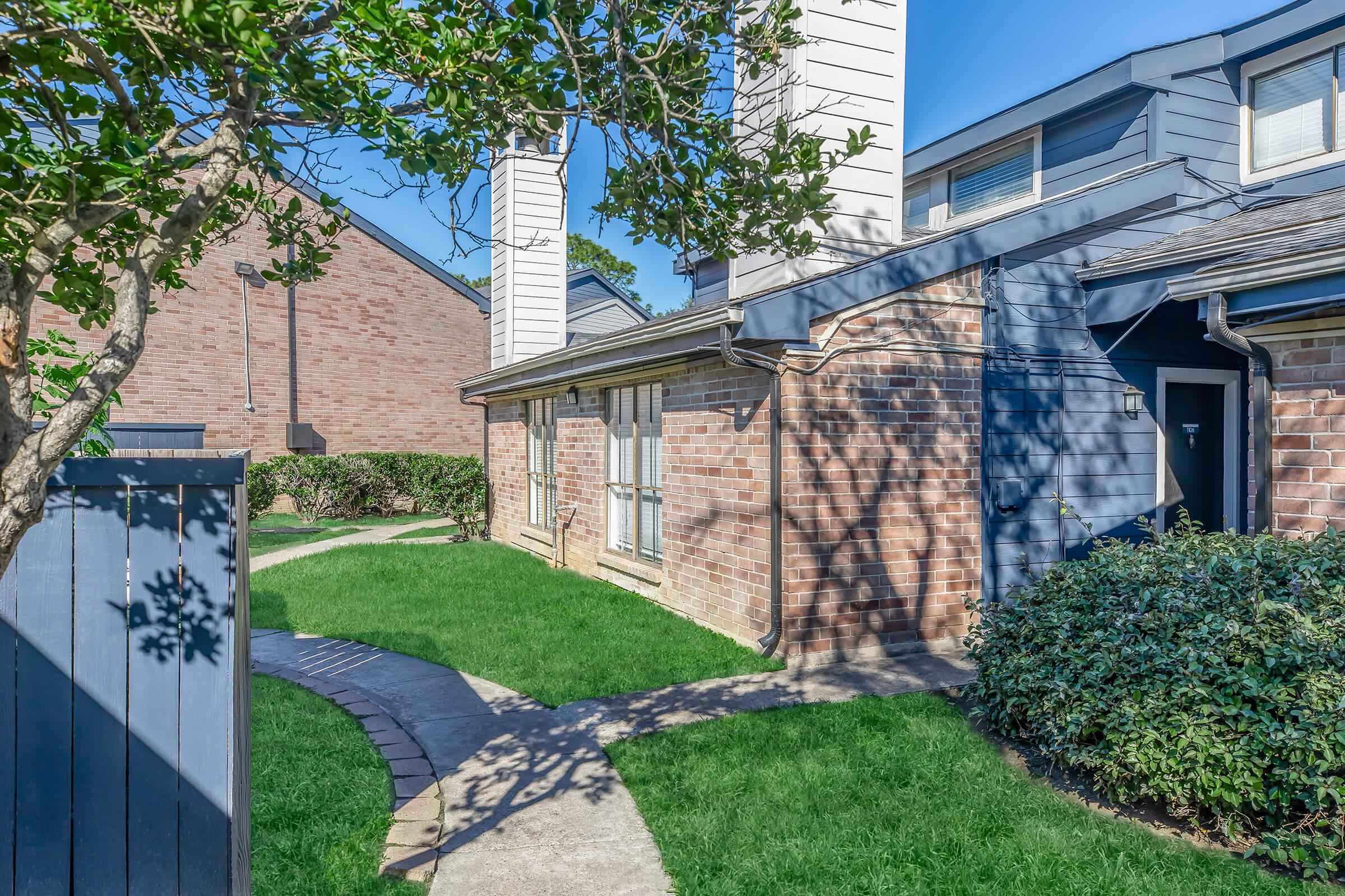 a large brick building with grass in front of a house