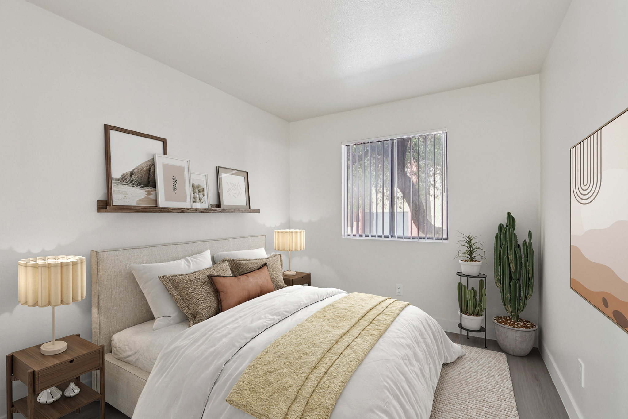 A cozy bedroom featuring a large bed with white bedding and decorative pillows. There are two bedside tables with lamps, a shelf with framed pictures on the wall, a potted cactus in the corner, and a large window with vertical blinds letting in natural light. Soft neutral colors create a serene atmosphere.