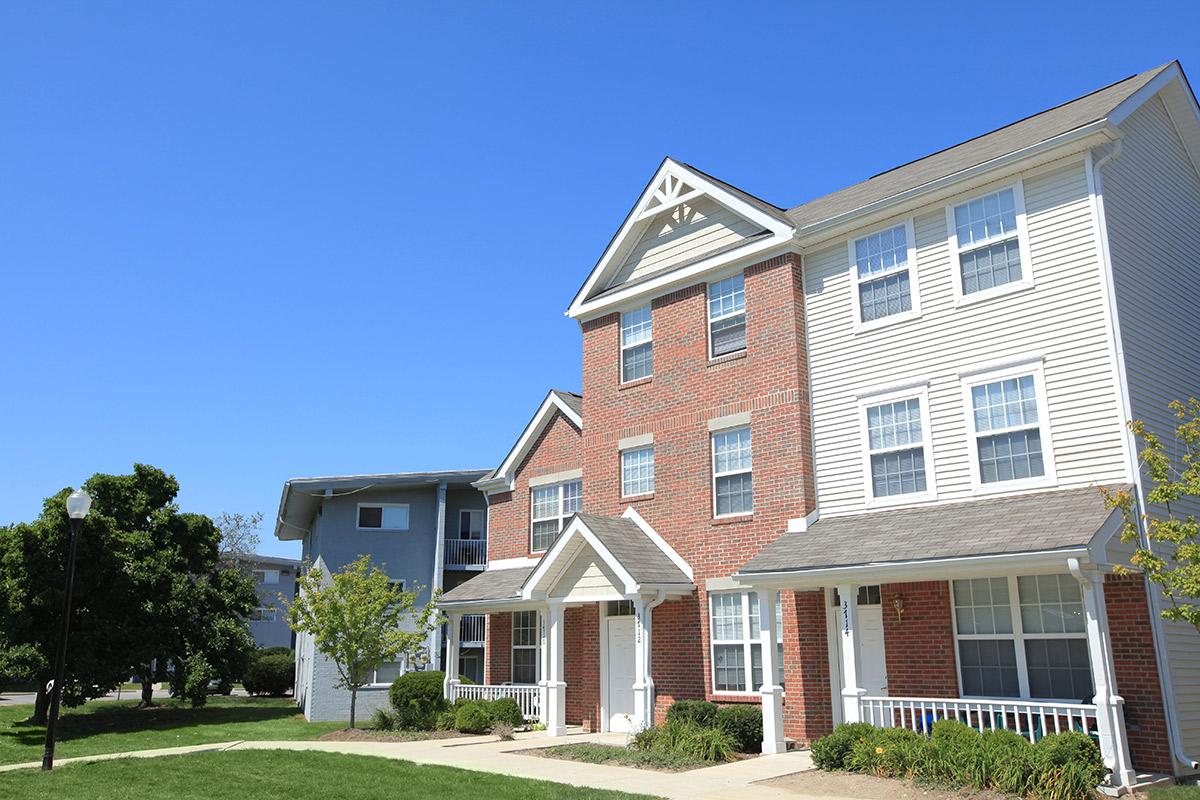 a large brick building with grass in front of a house