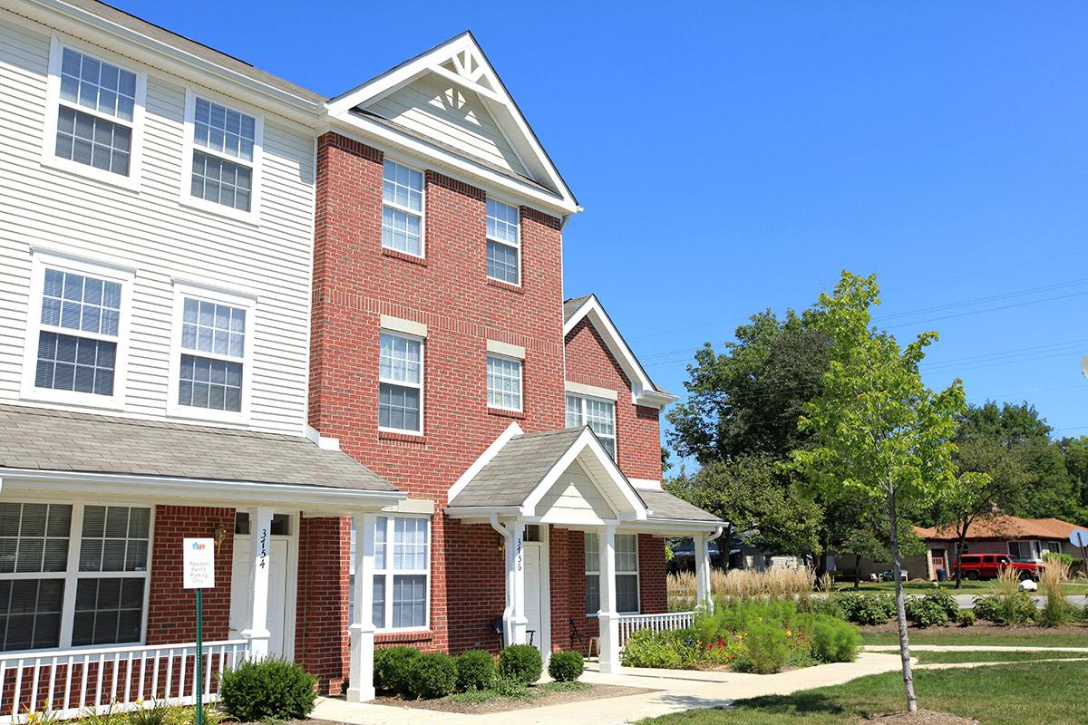 a large brick building with grass in front of a house