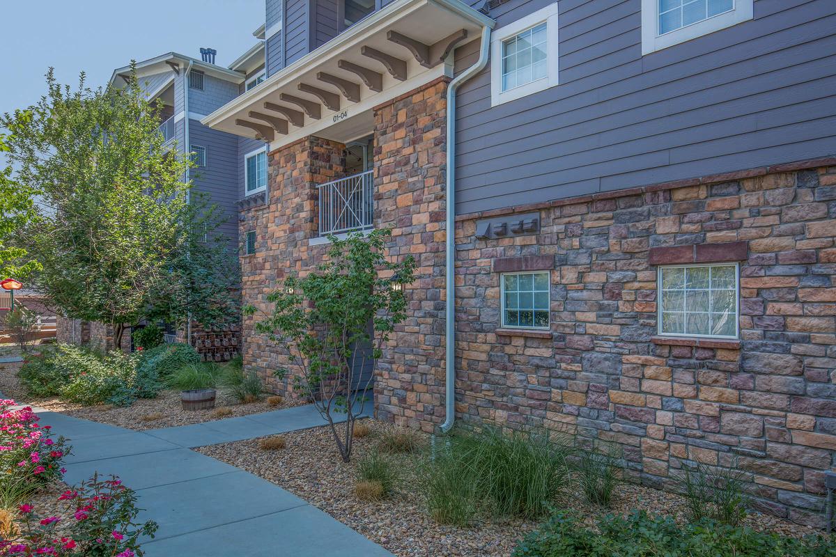 a house with bushes in front of a brick building