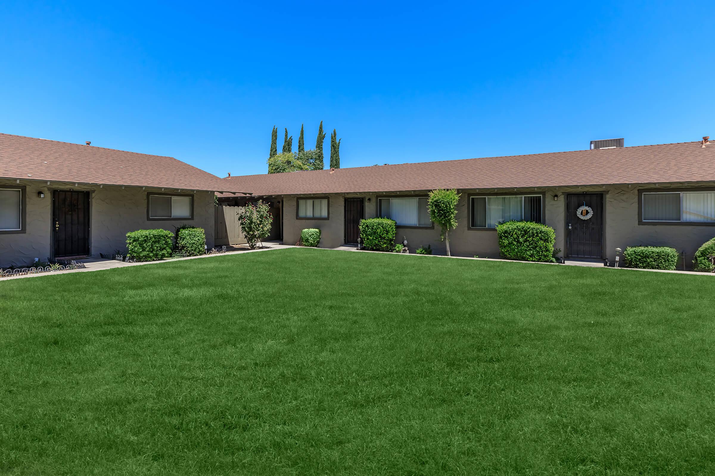 a large brick building with grass in front of a house