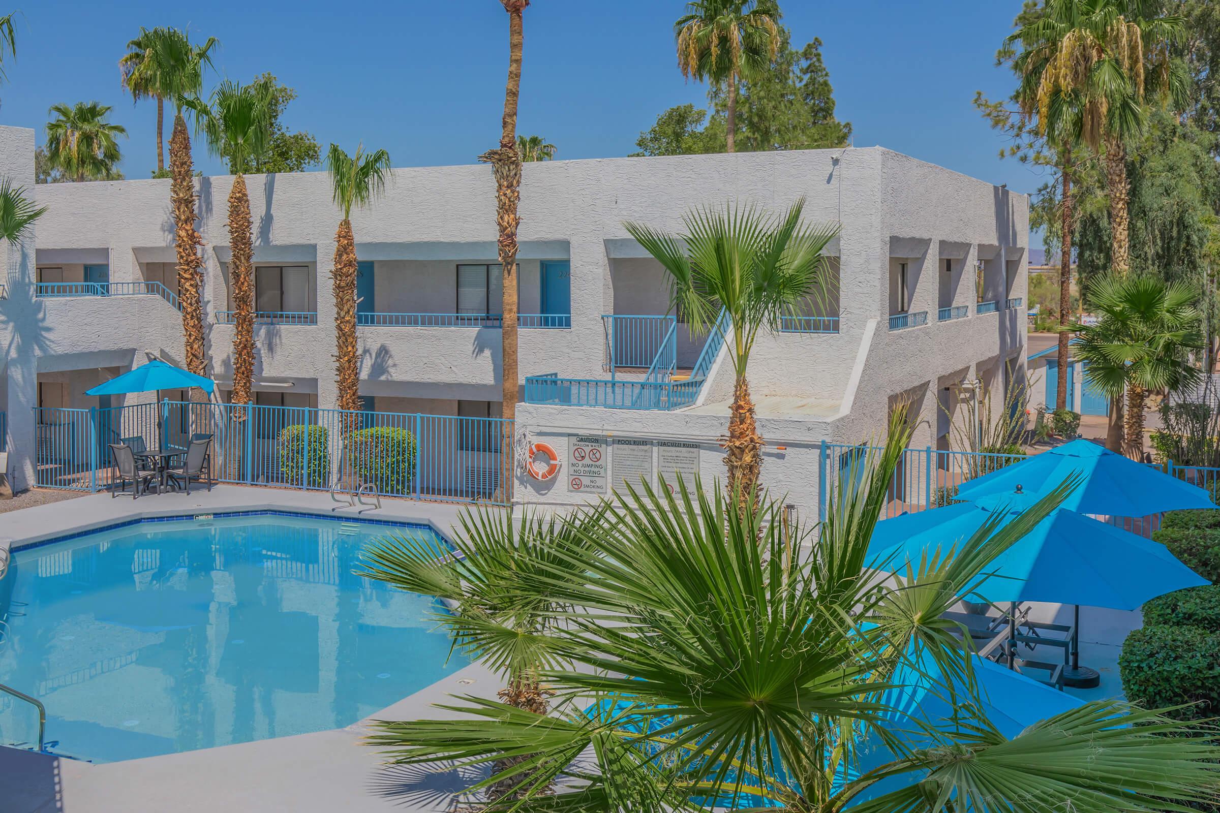 a building with a pool in front of a palm tree