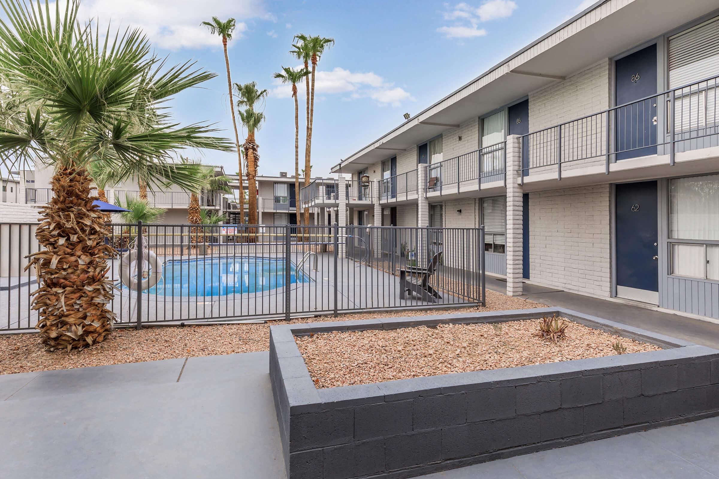 a building with palm trees and a fence