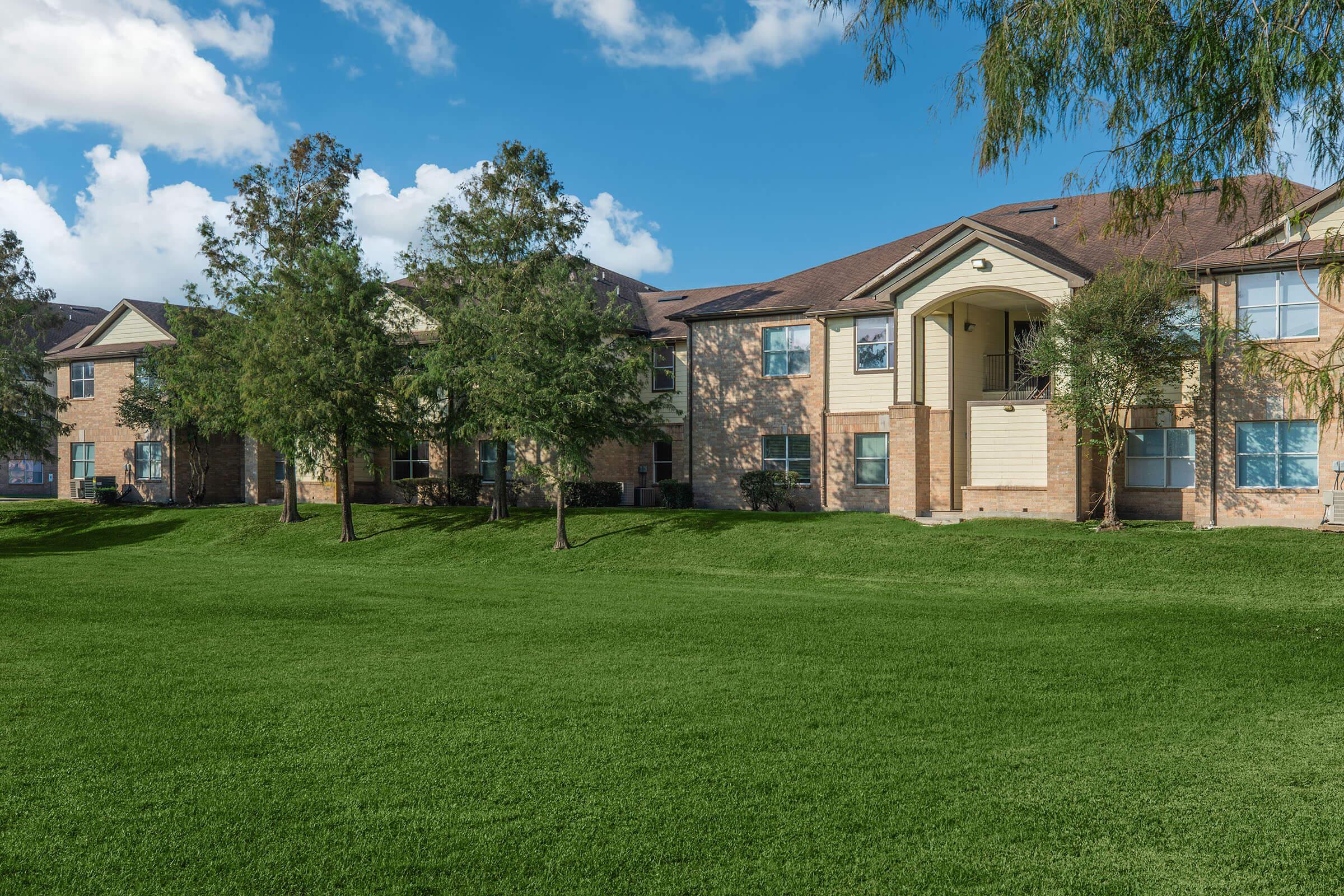 a large brick building with green grass in front of a house