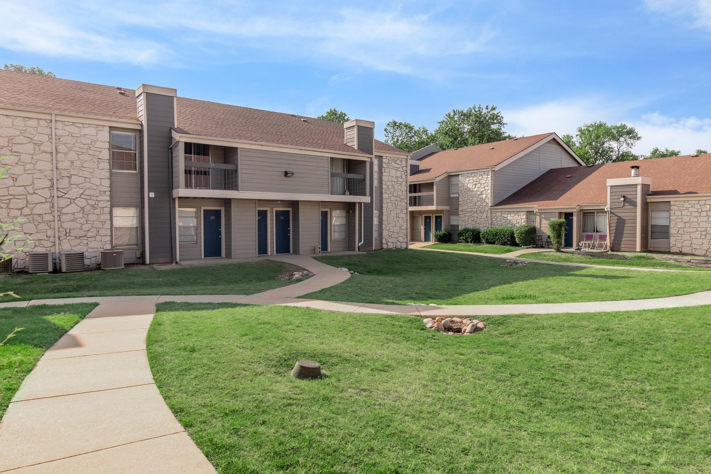 a house with a lawn in front of a brick building