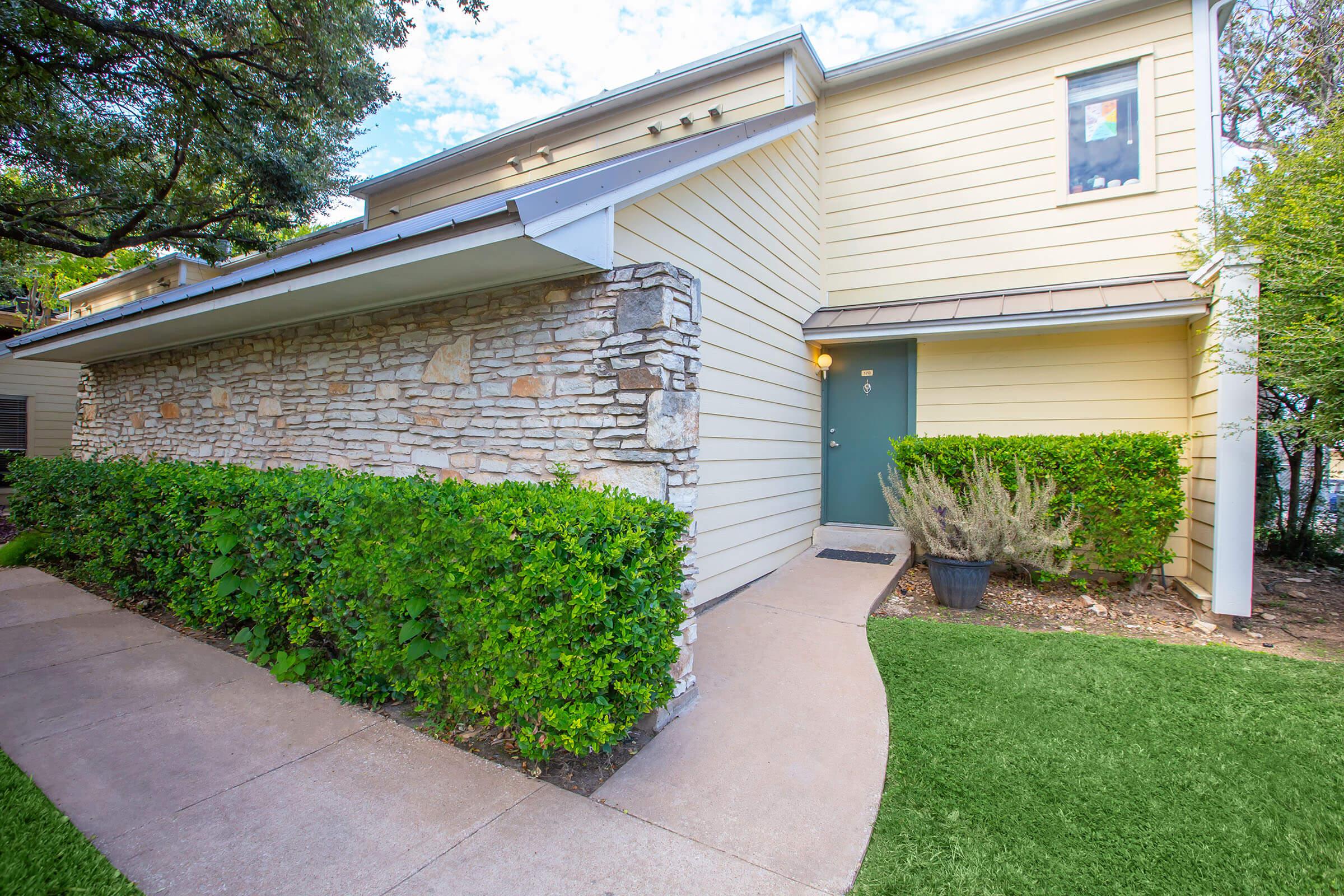 a house with a lawn in front of a brick building