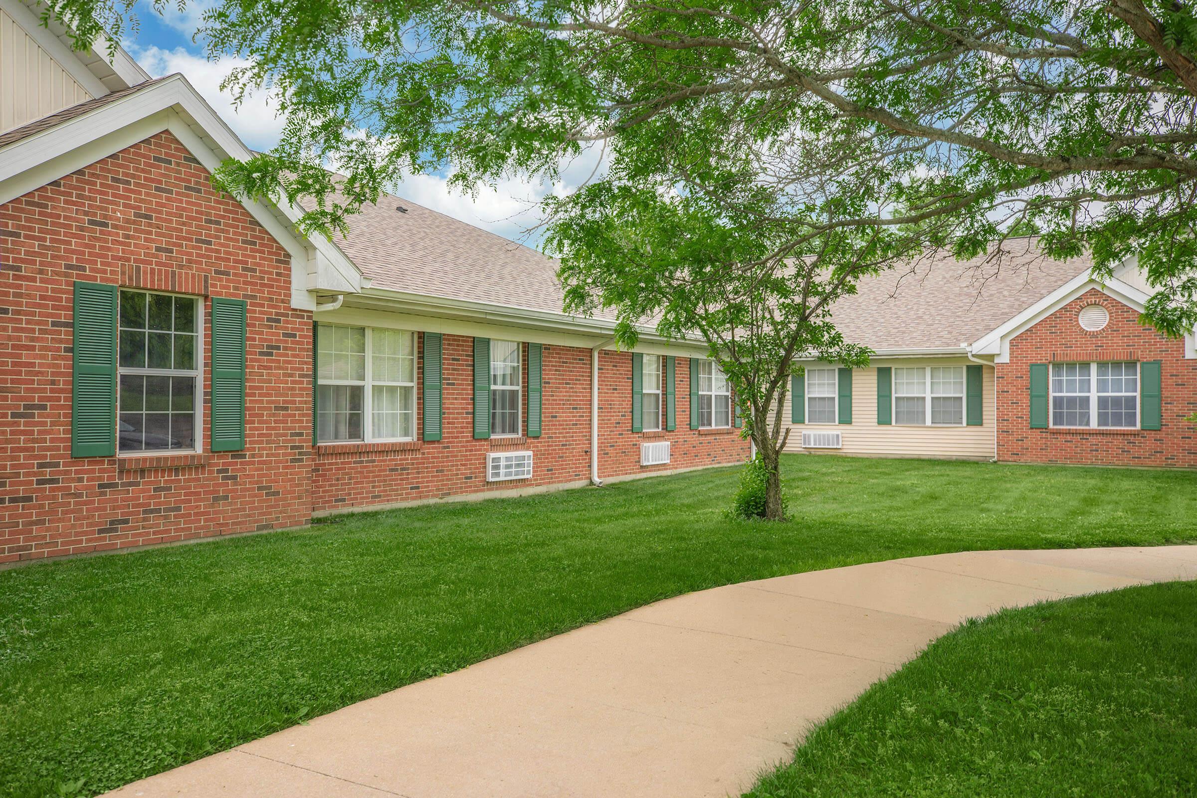 a house with a lawn in front of a brick building