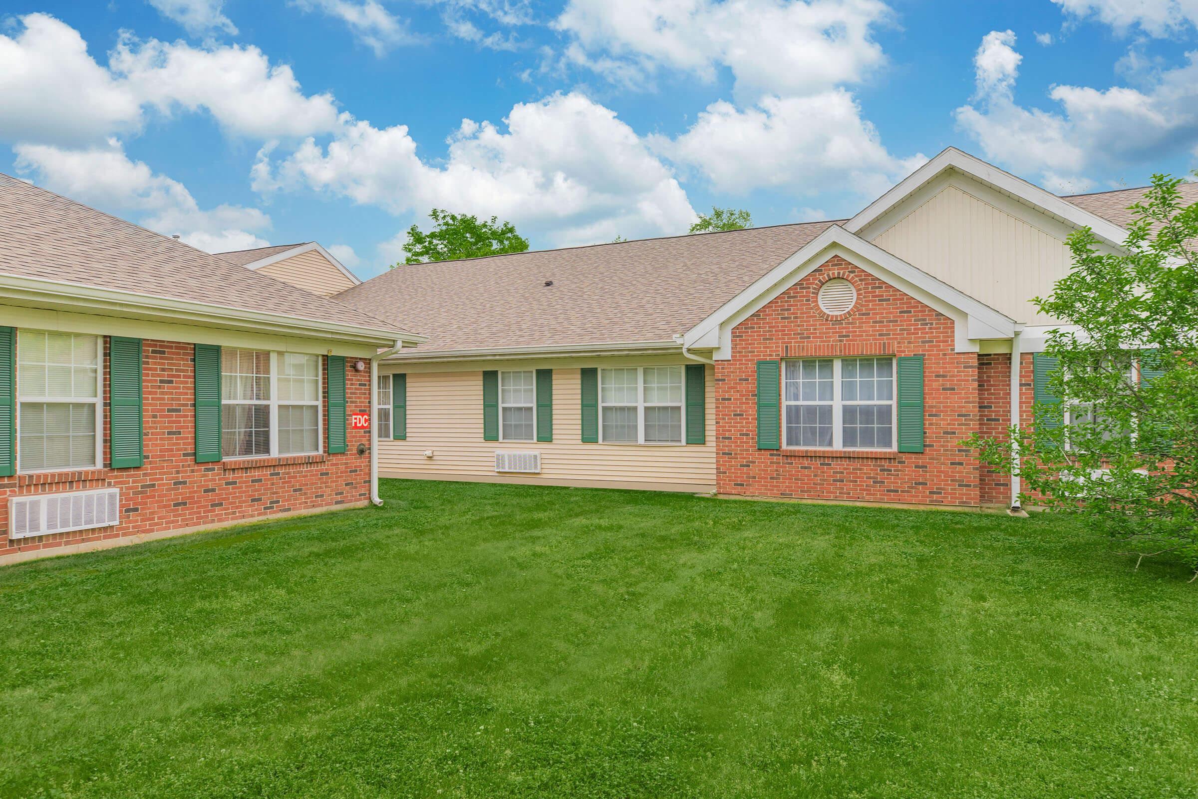 a large brick building with green grass in front of a house