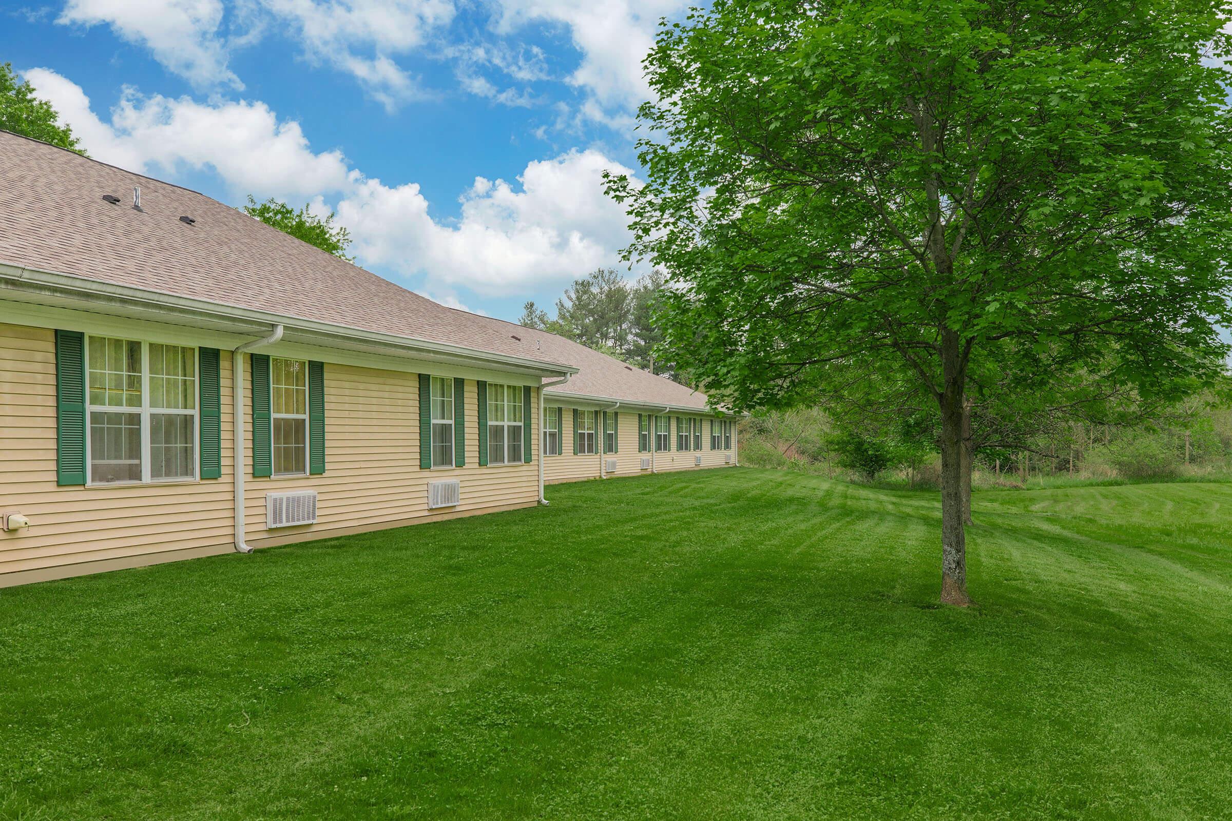 a large brick building with a grassy field