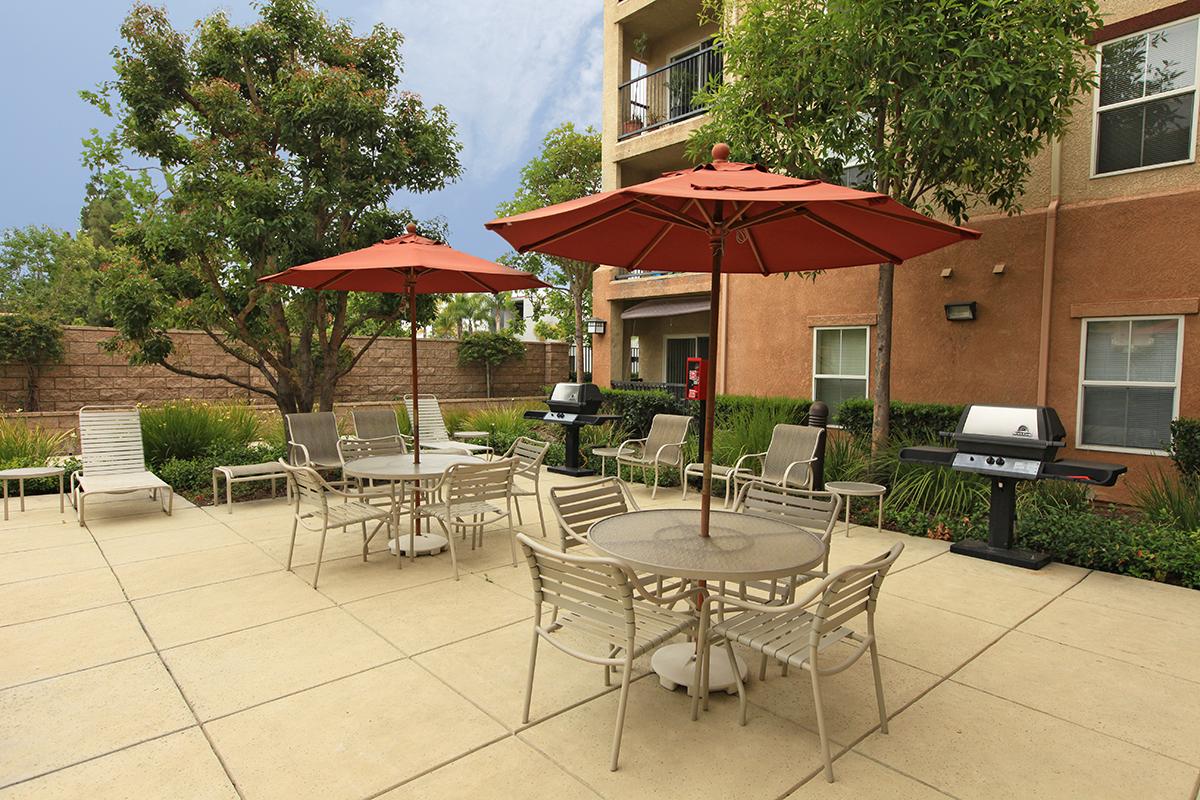 Two barbecues next to tables and chairs 