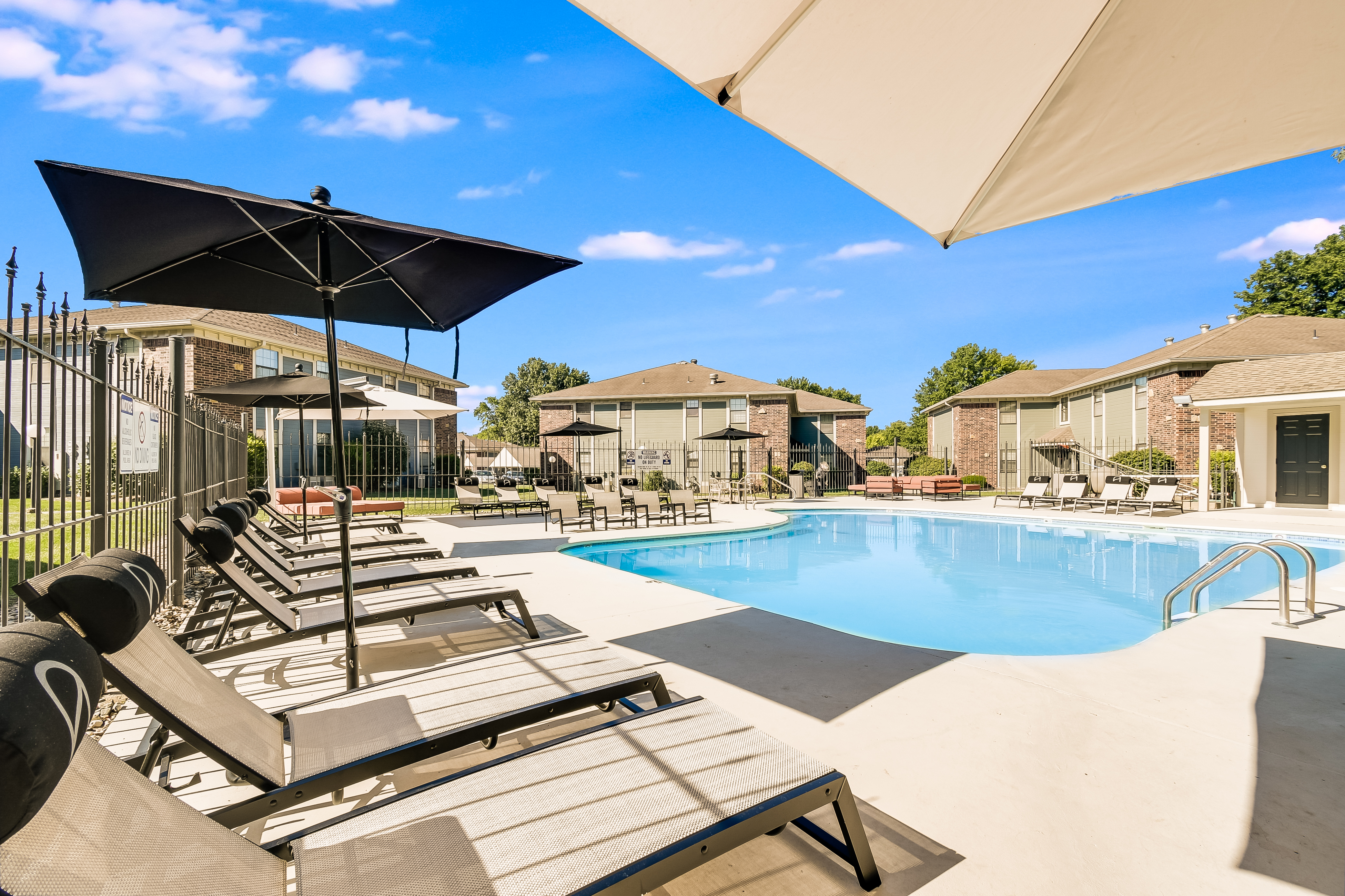 Tanning chairs and umbrellas in poolside lounge area at The Arbor in Blue Springs, Missouri