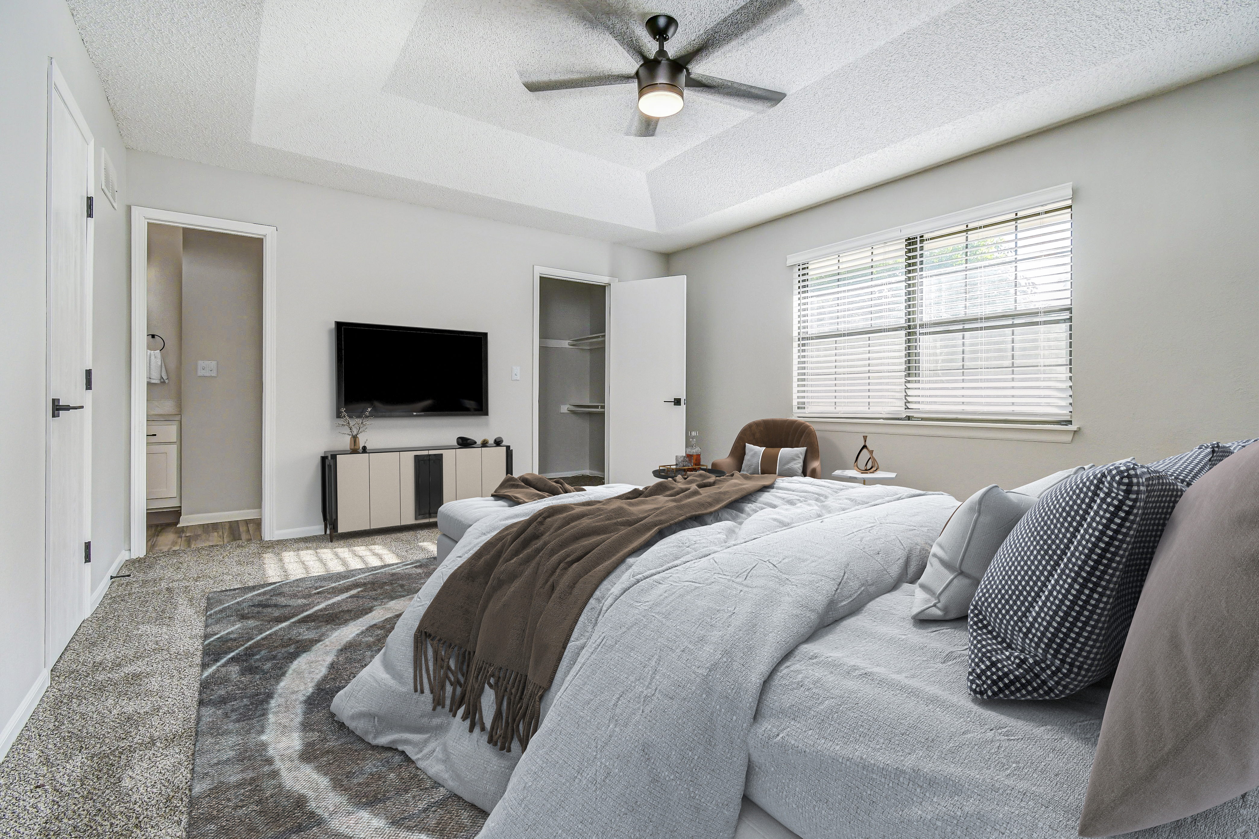 Furnished townhome platinum bedroom interior with wall-mounted TV at The Arbor in Blue Springs, MO