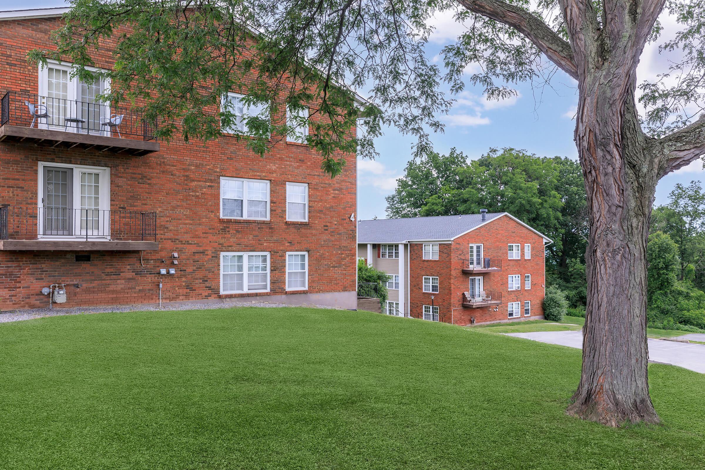 a large brick building with grass in front of a house