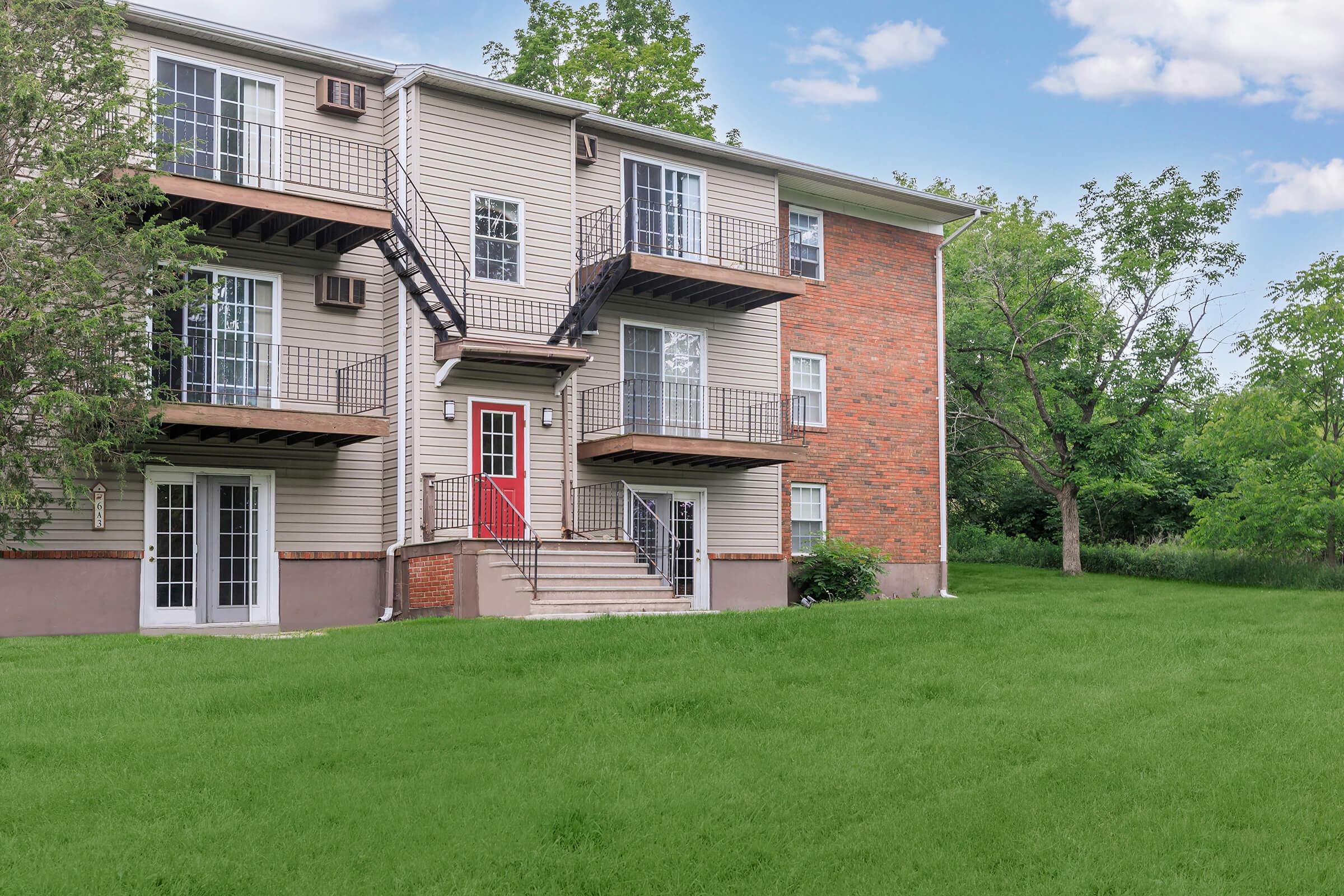 a large brick building with grass in front of a house