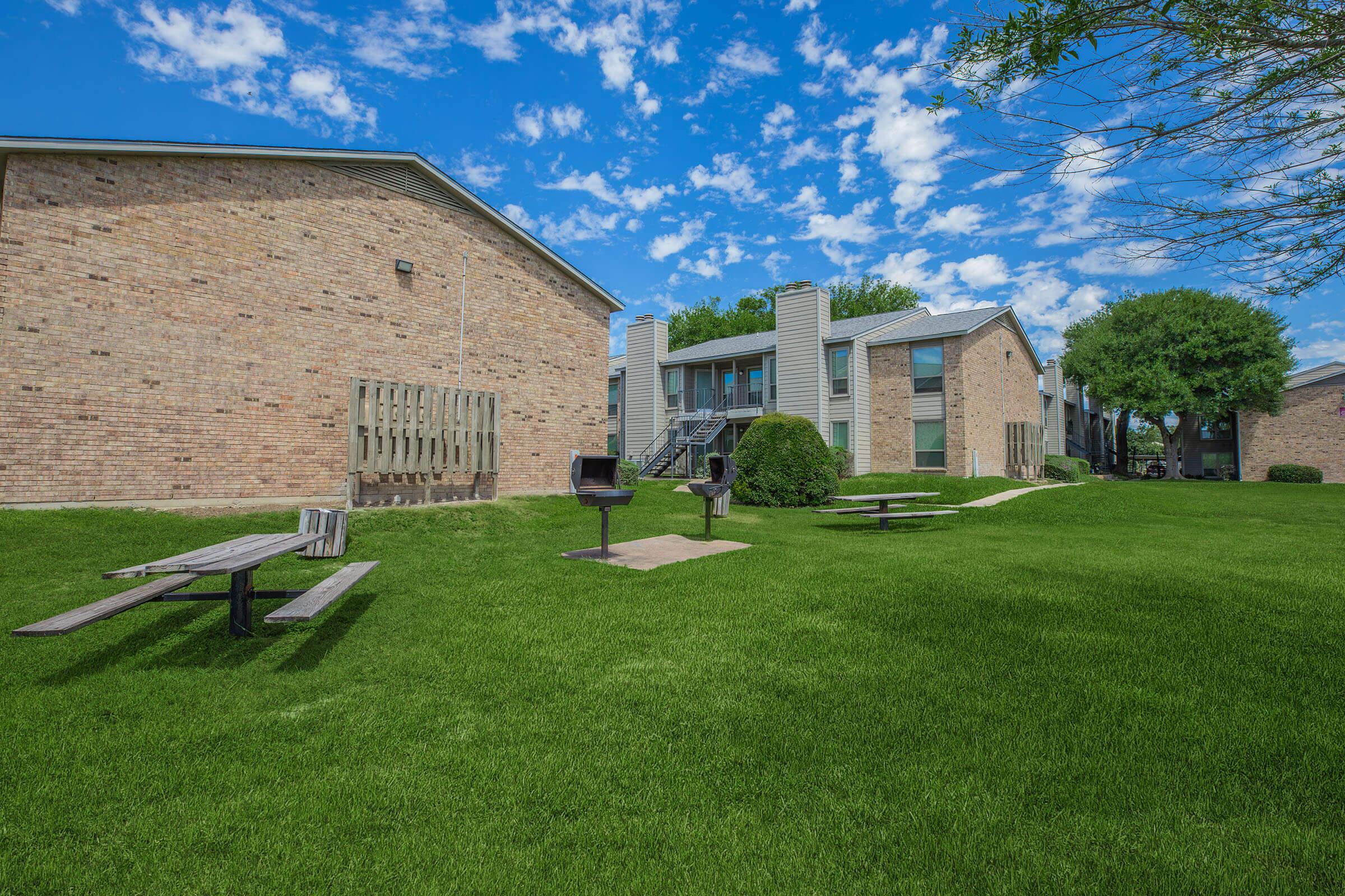 a large brick building with green grass in front of a house