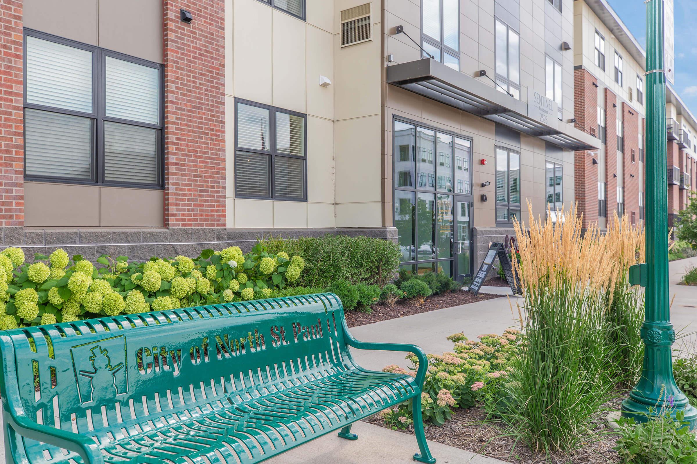 a green bench sitting in front of a building