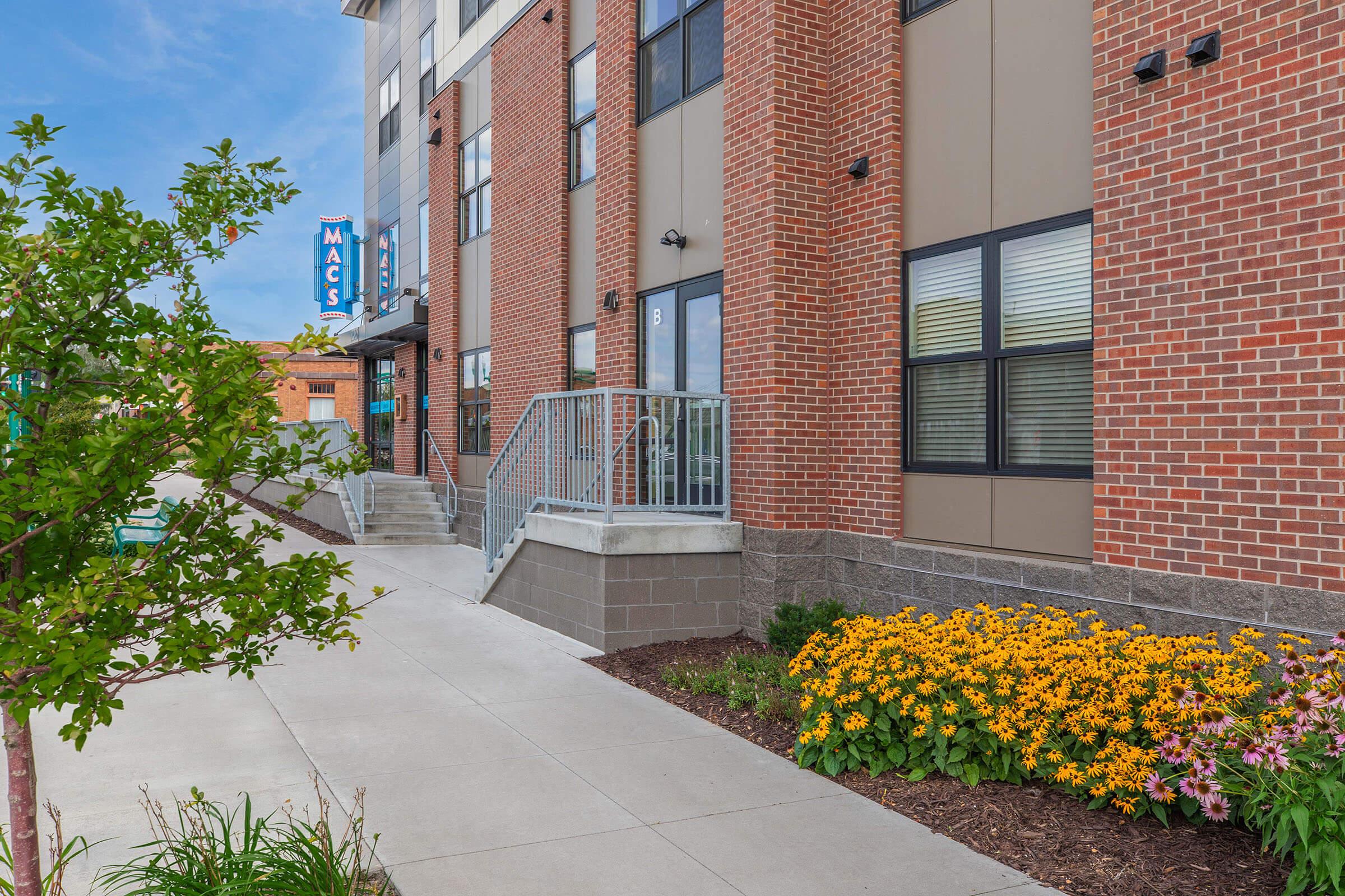 a close up of a flower garden in front of a brick building