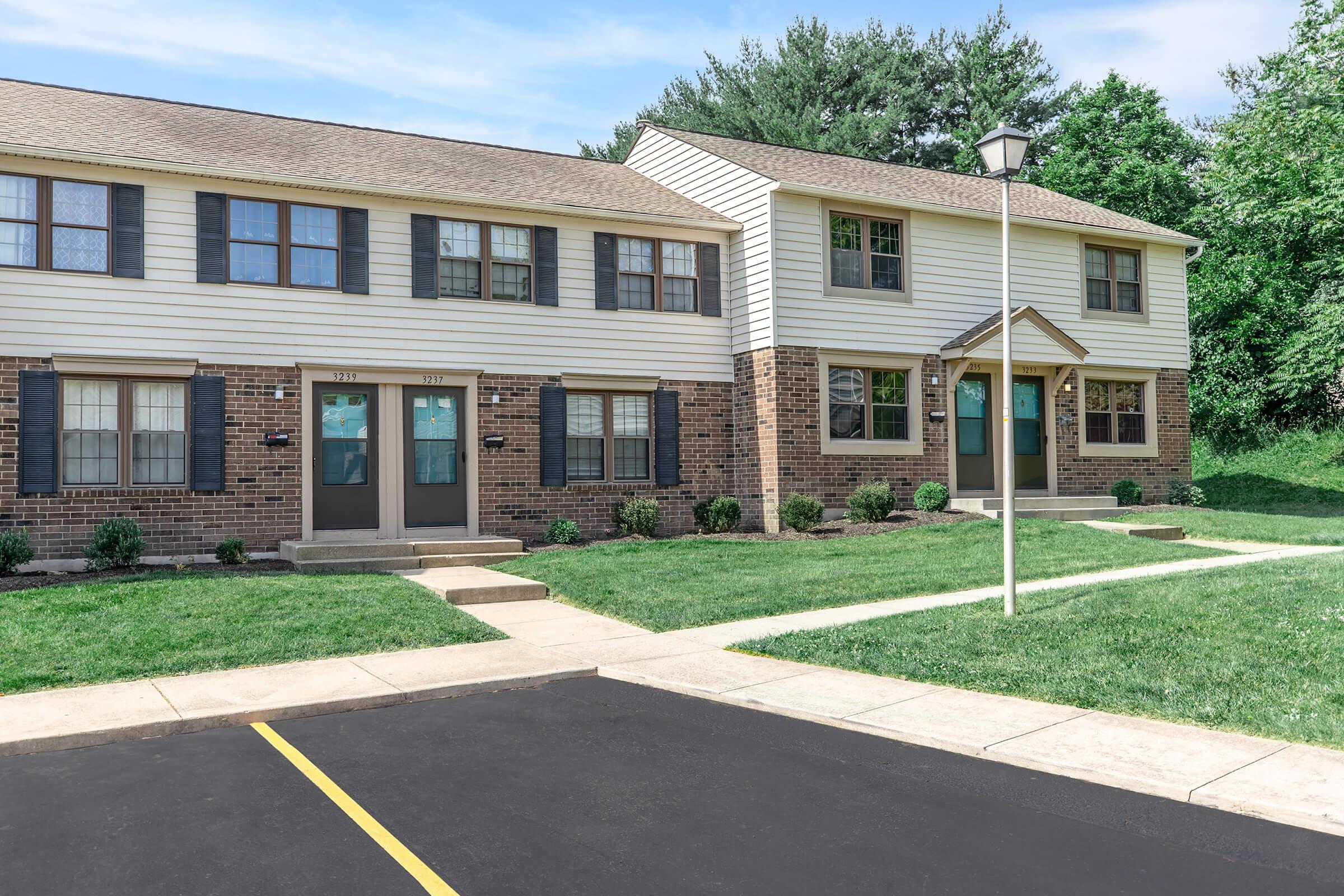 a large brick building with grass in front of a house