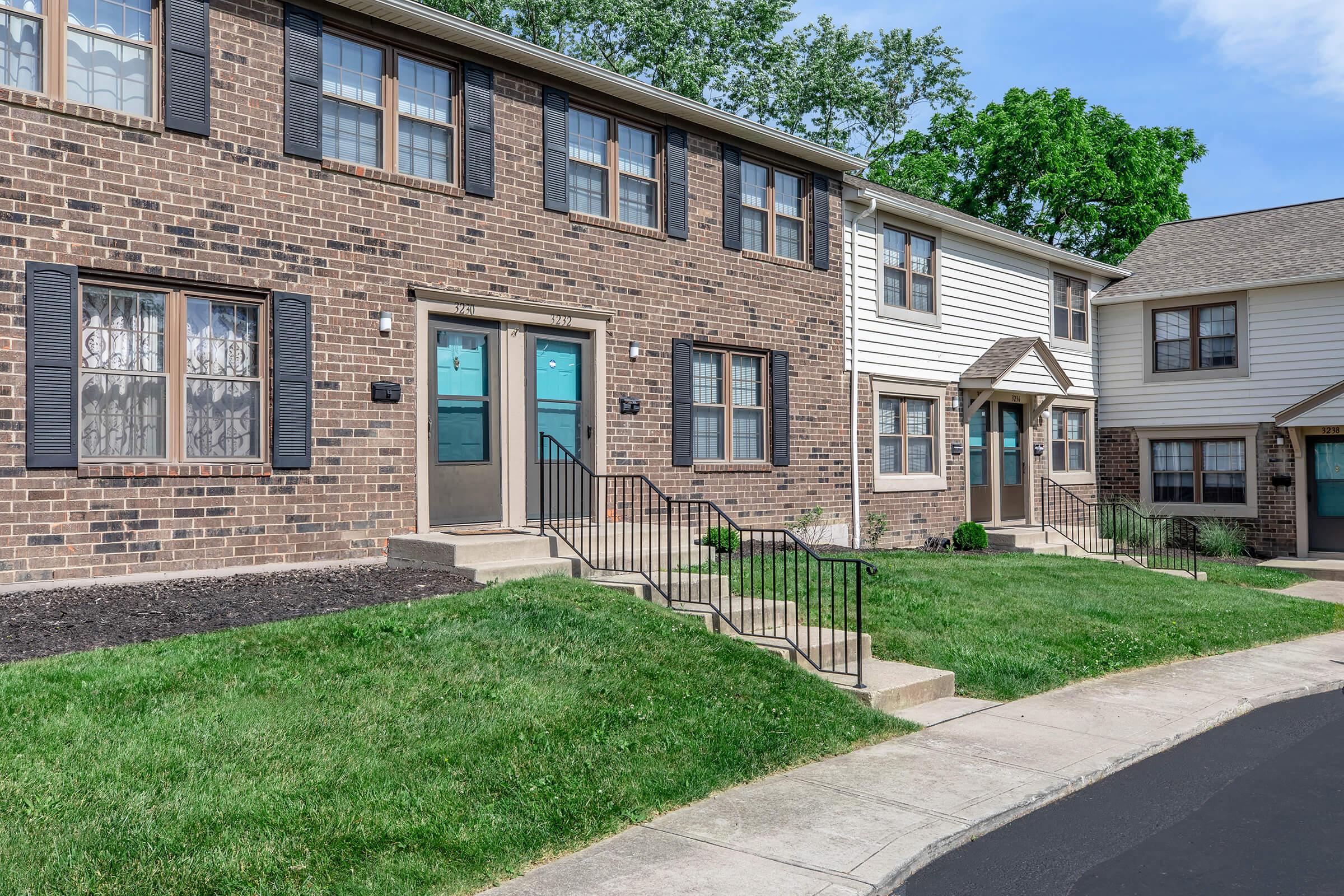 a large brick building with grass in front of a house