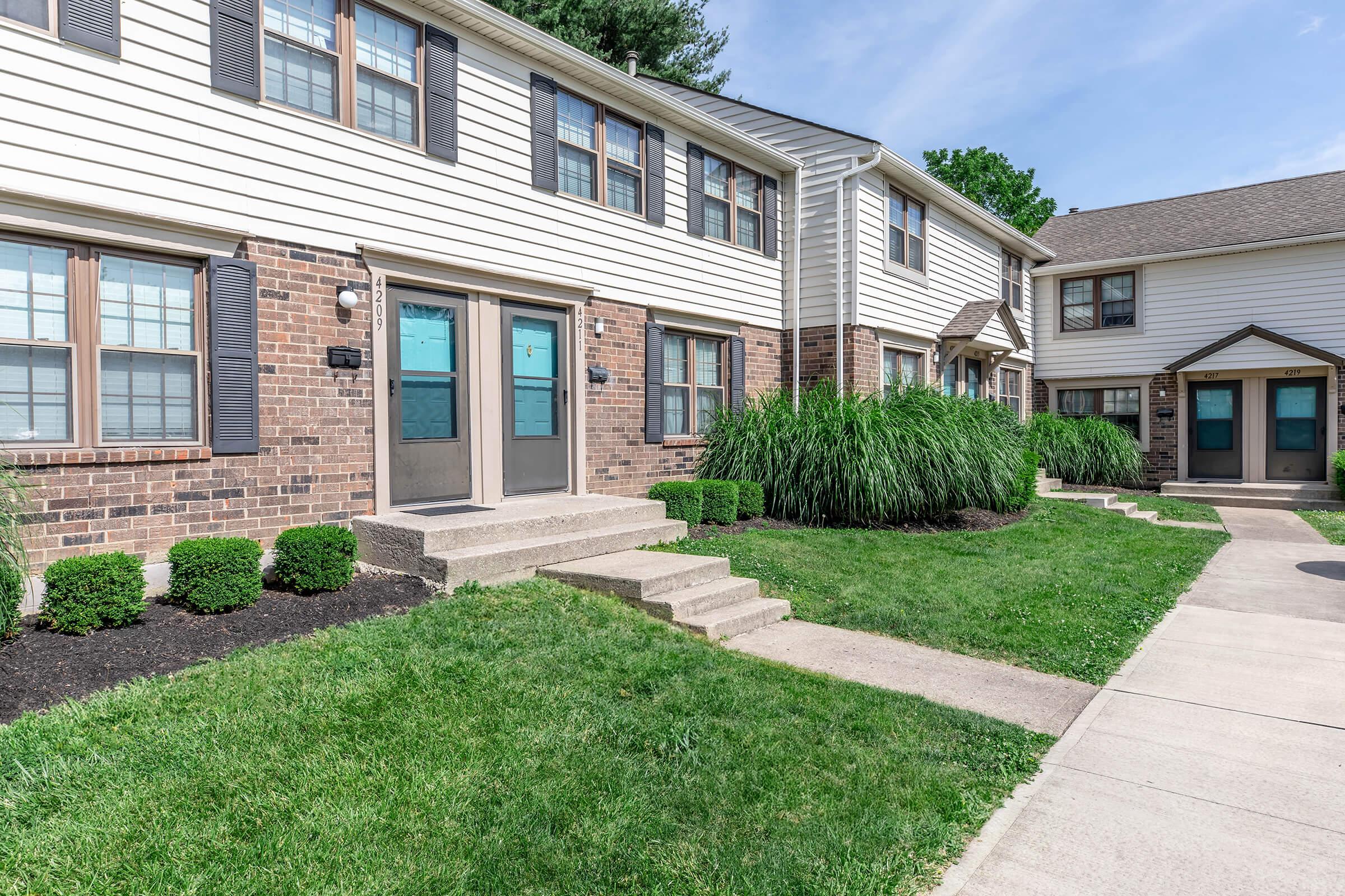 a large brick building with grass in front of a house