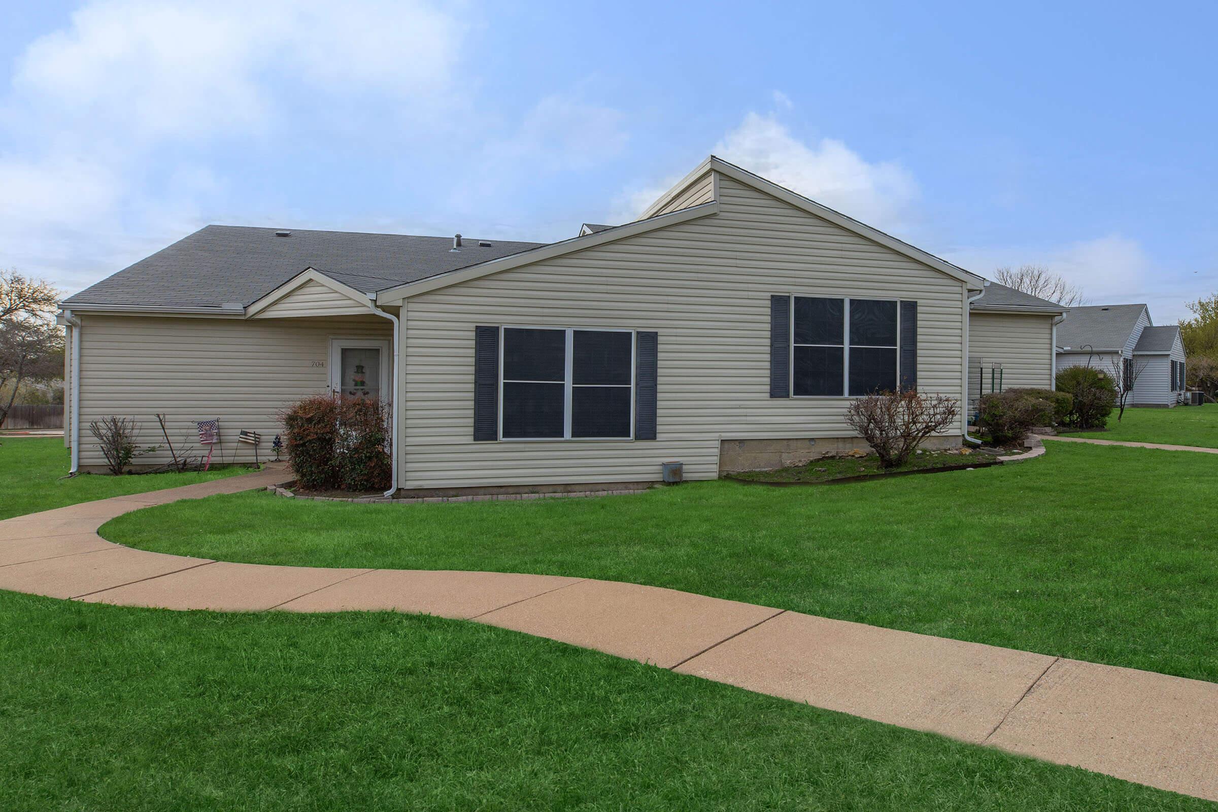 a house with a lawn in front of a brick building