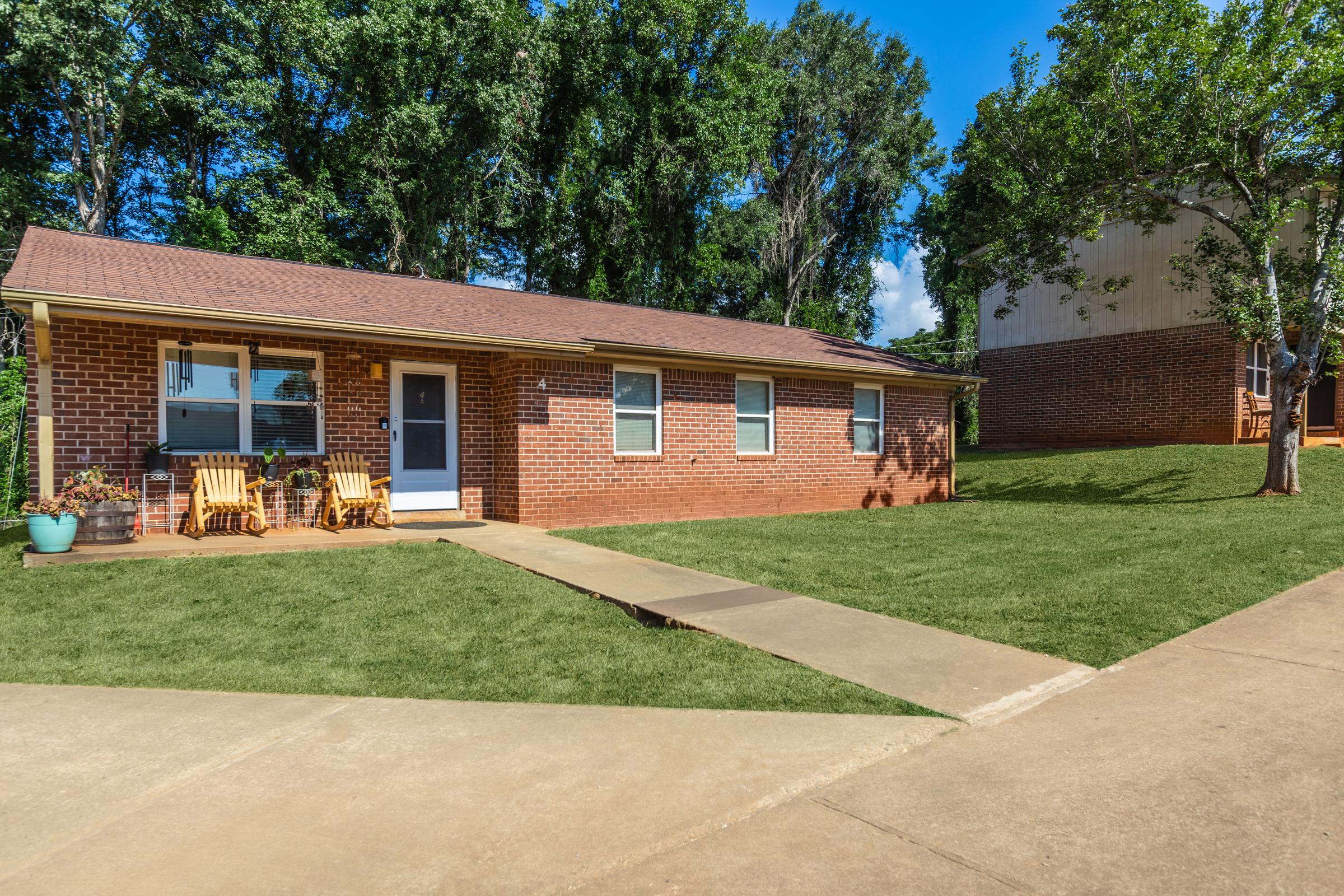 a house with a lawn in front of a brick building