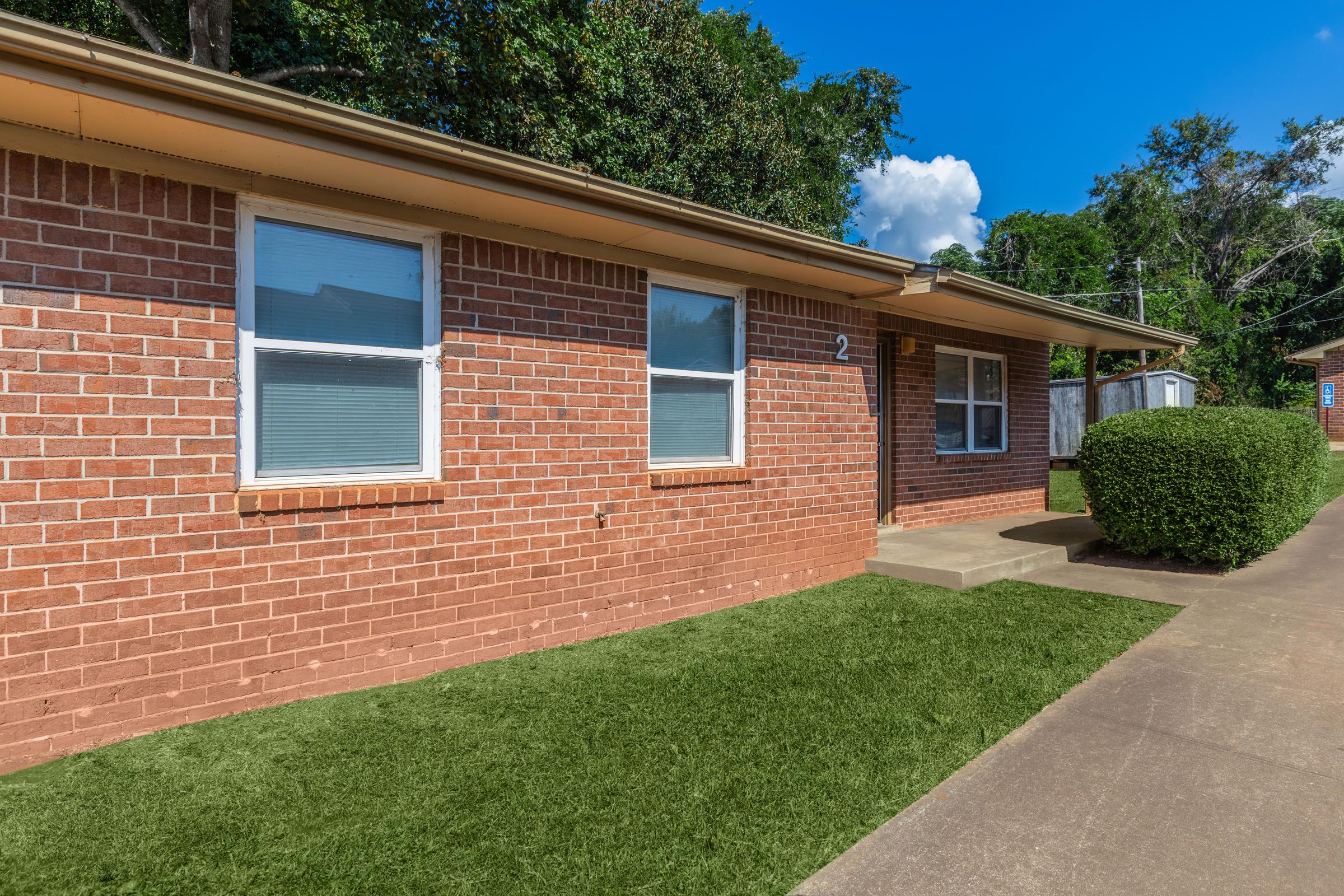 a large brick building with grass in front of a house