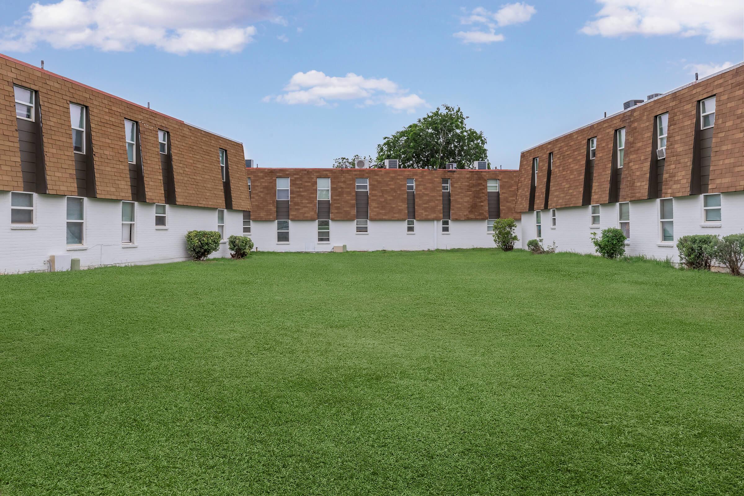 a large brick building with green grass