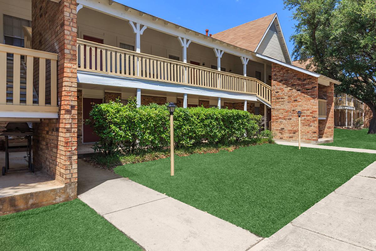 a large brick building with grass in front of a house