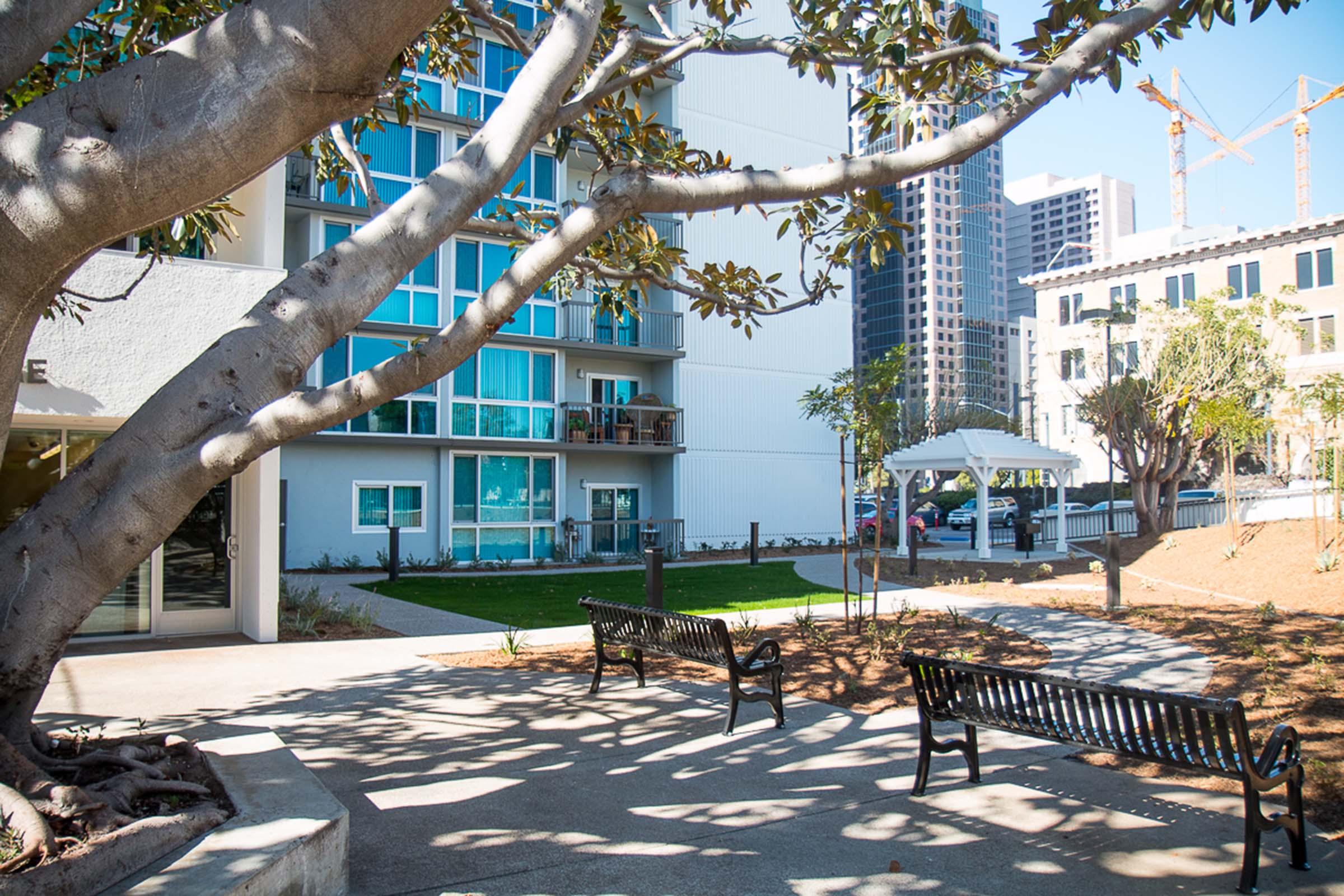 Courtyard with benches and trees, with a gazebo in the background.