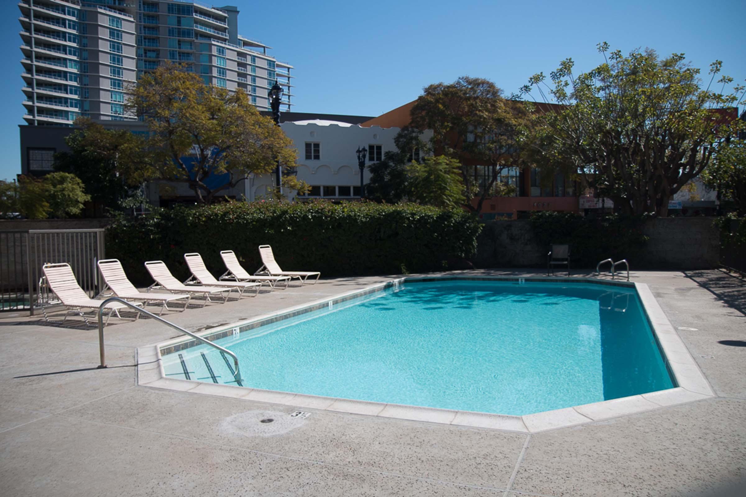 Shimmering blue swimming pool with deck chairs nearby.