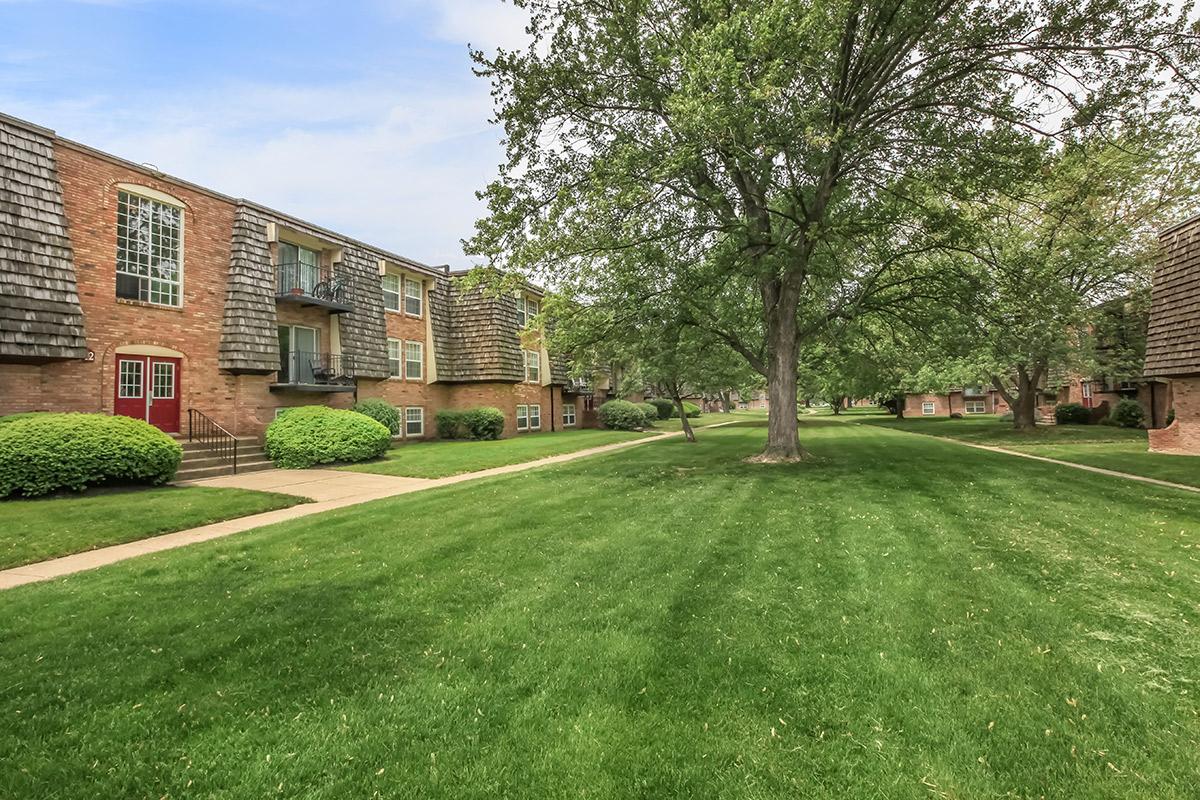 a large brick building with green grass in front of a house