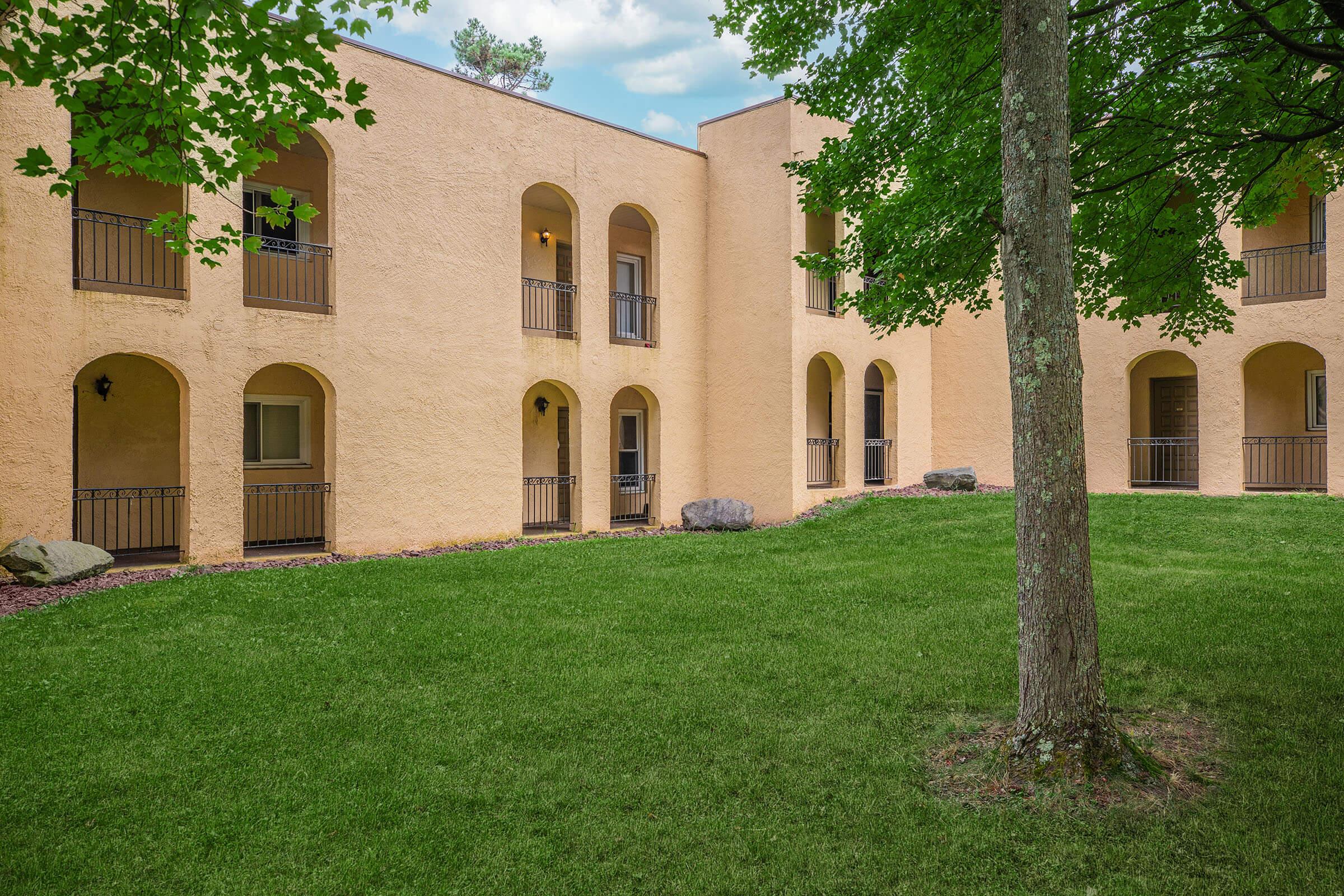 a large brick building with grass in front of a house