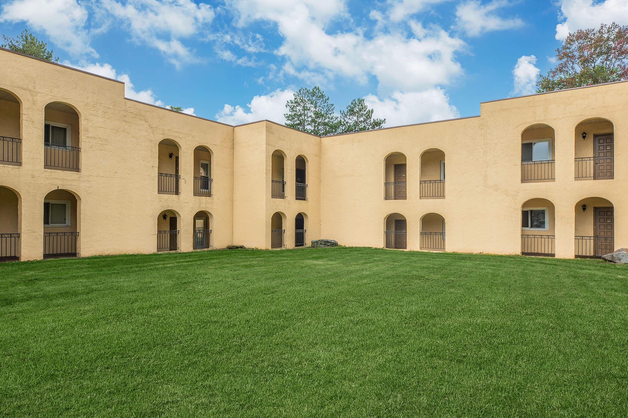 a large brick building with green grass in front of a house