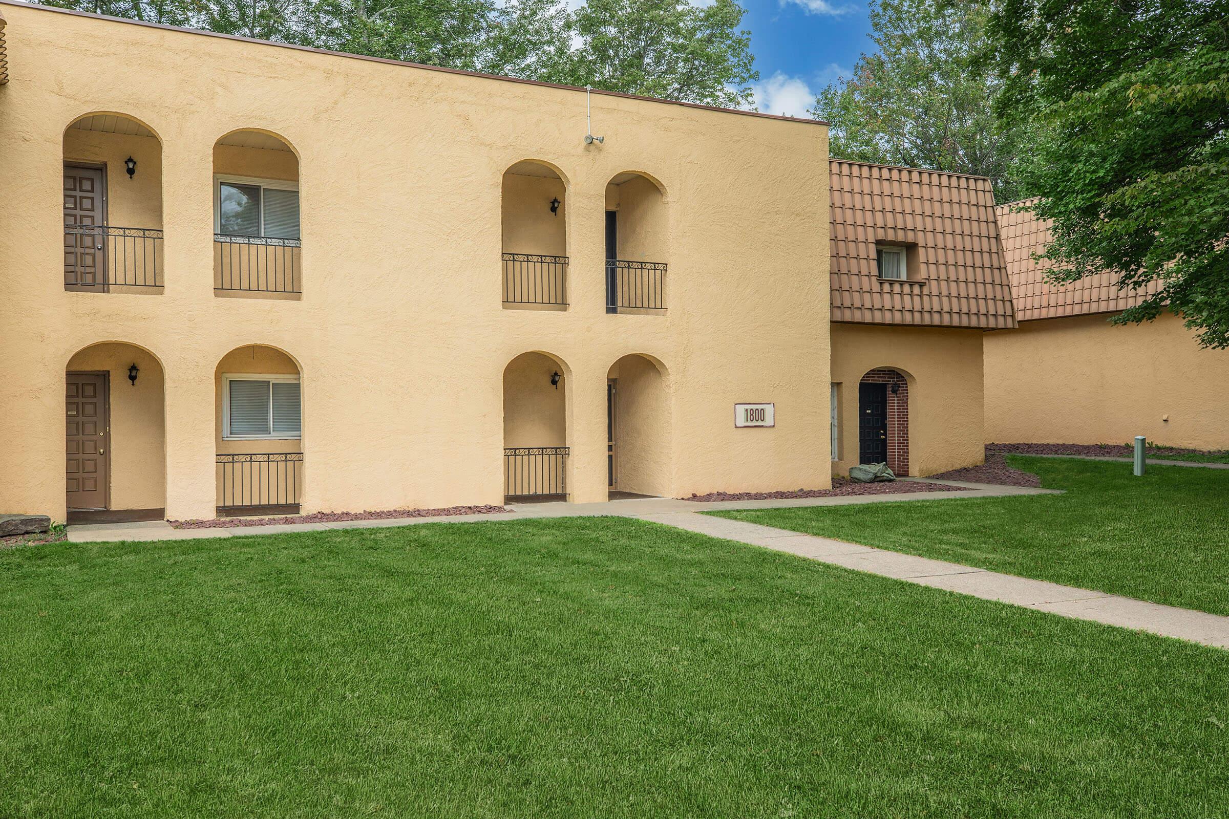 a large brick building with green grass in front of a house