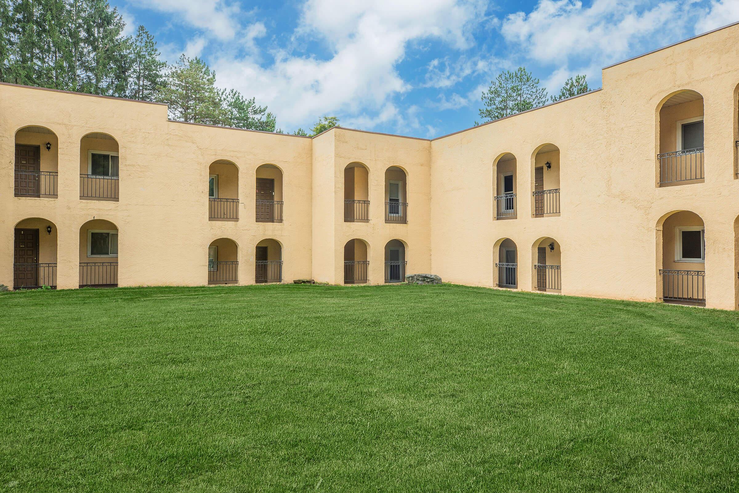 a large brick building with grass in front of a house