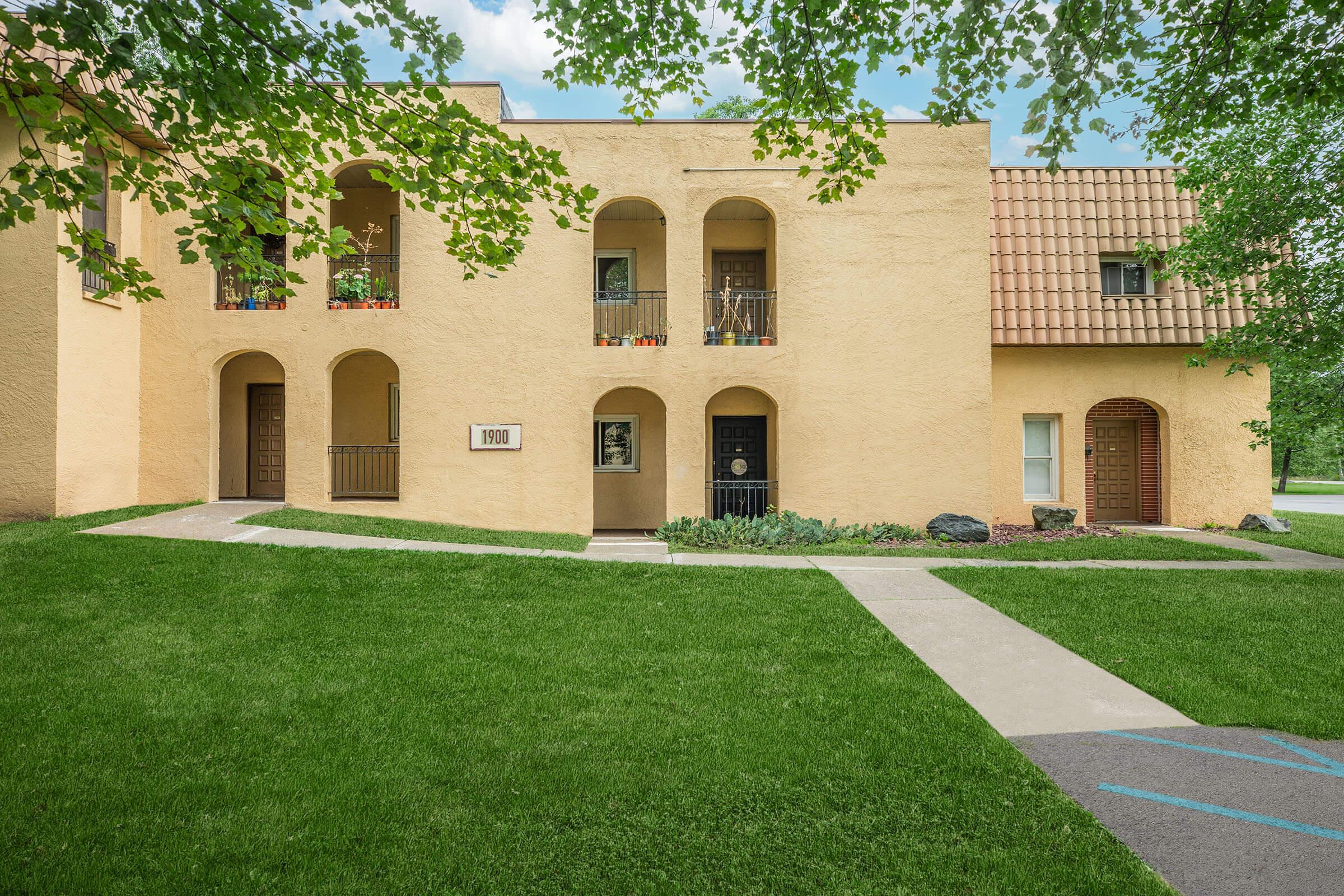 a large brick building with grass in front of a house