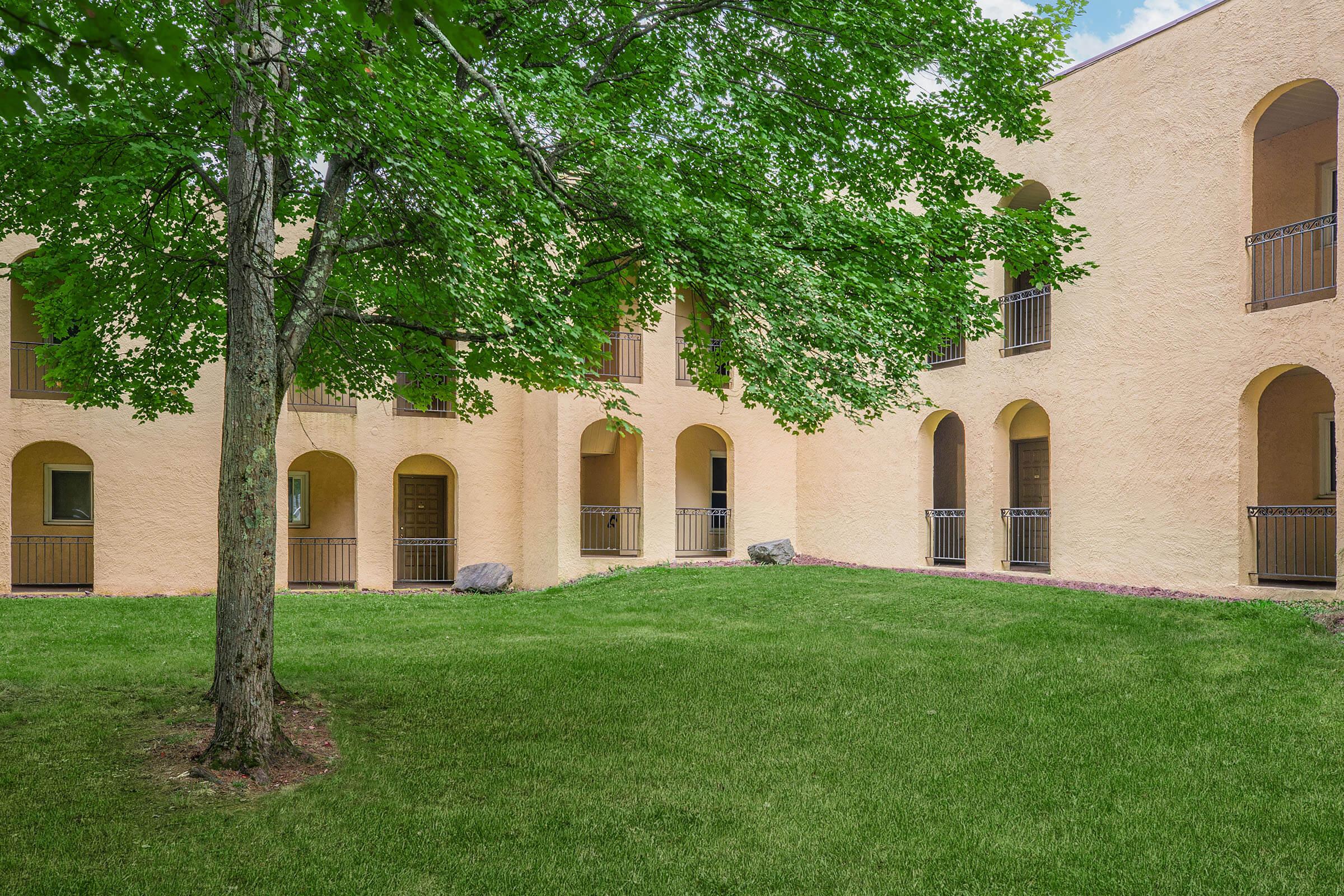 a large brick building with grass in front of a house