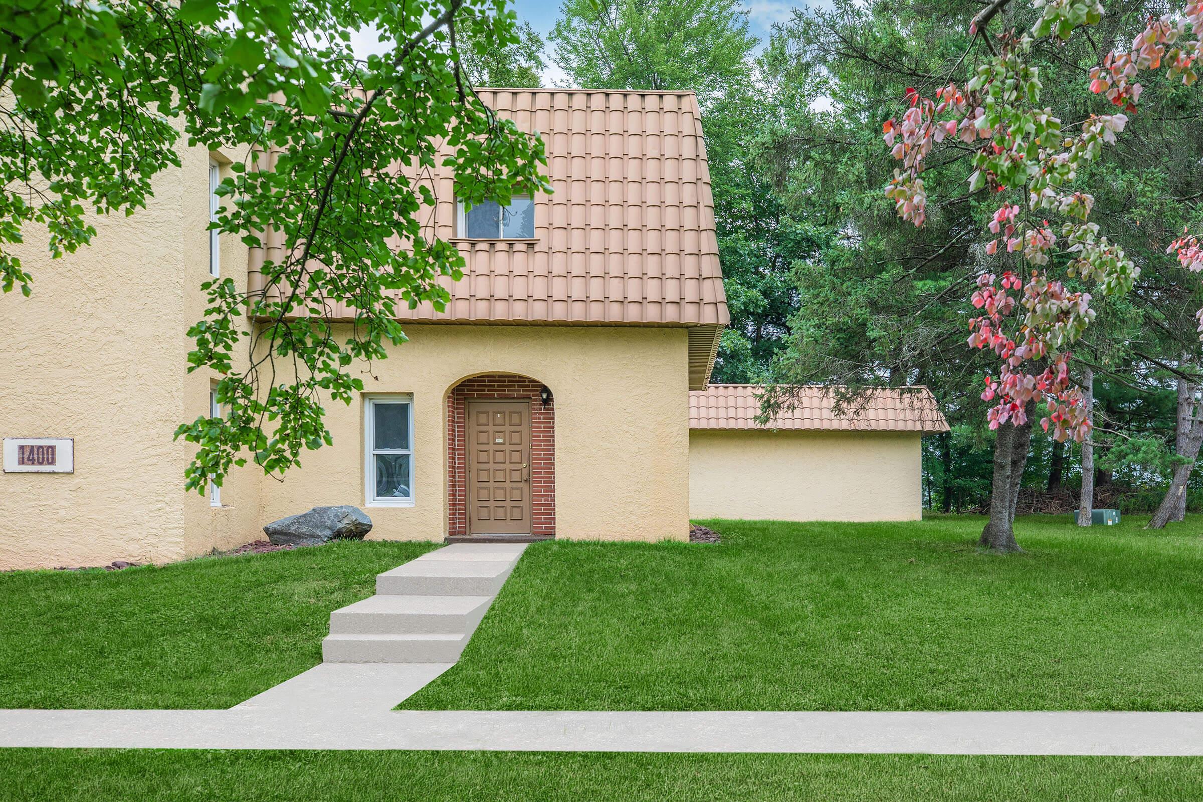 a house with a lawn in front of a brick building