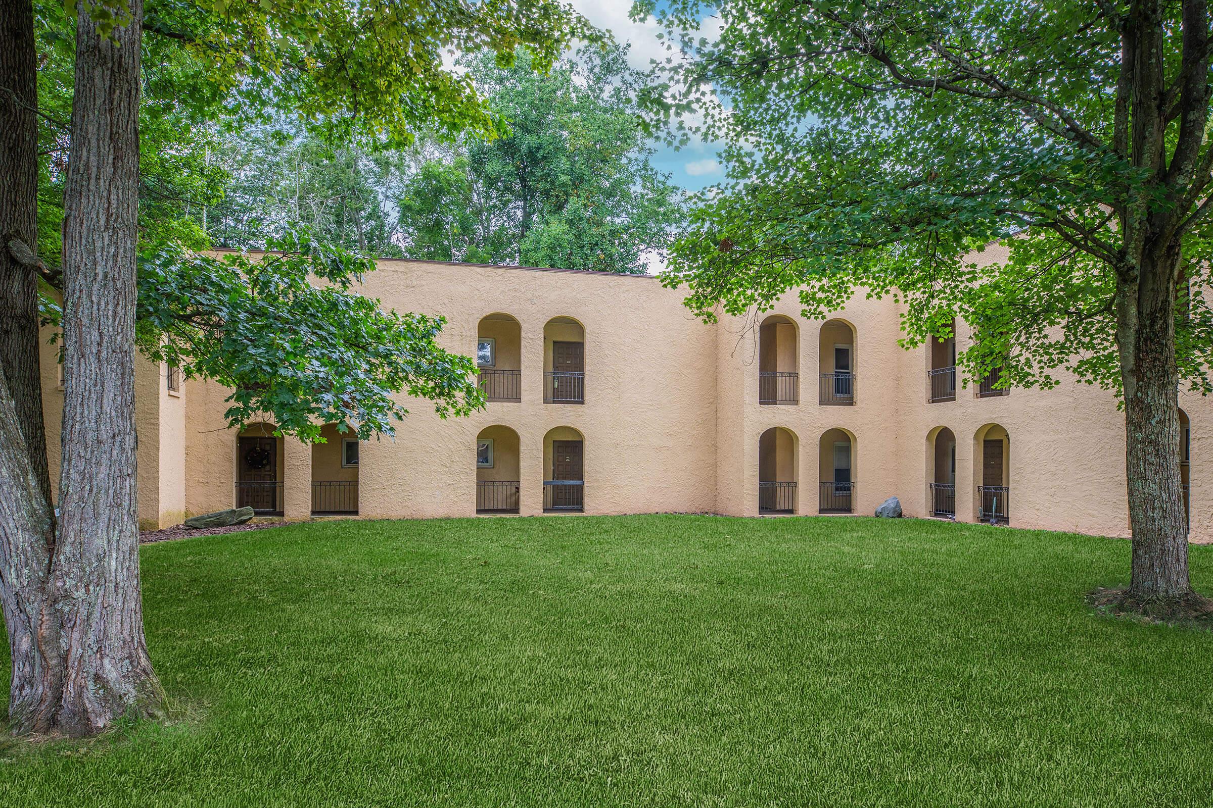 a large brick building with green grass and trees