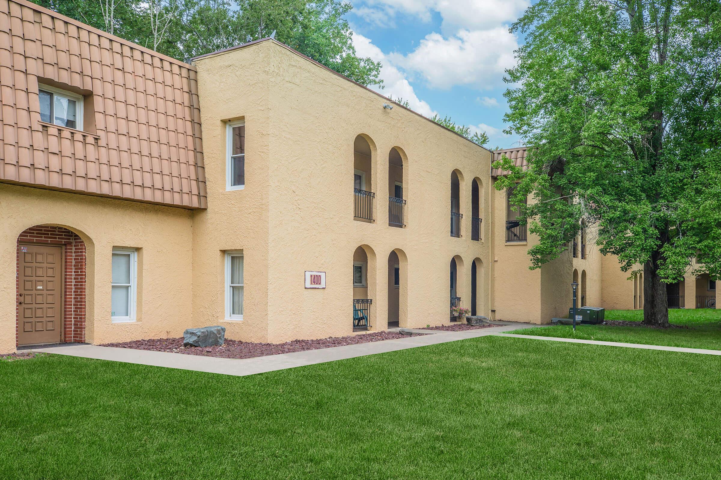 a large brick building with grass in front of a house