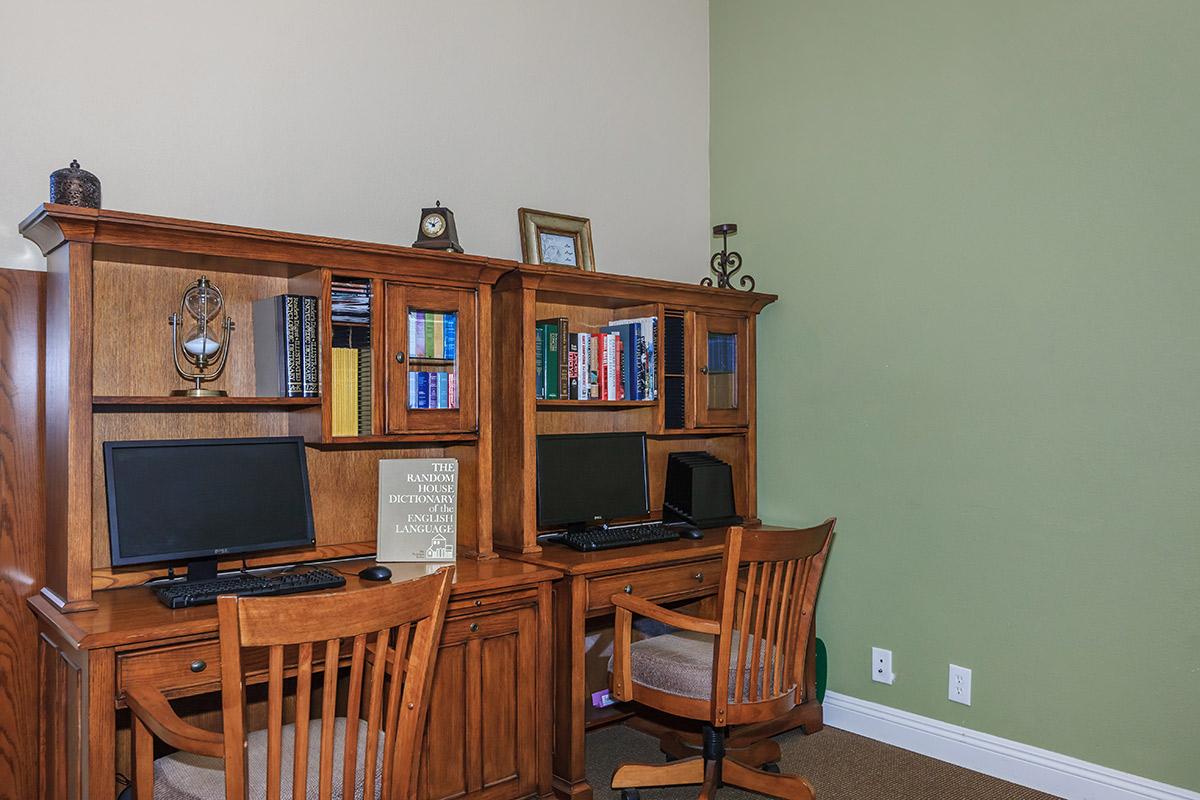 a desk with a laptop computer sitting on top of a wooden chair